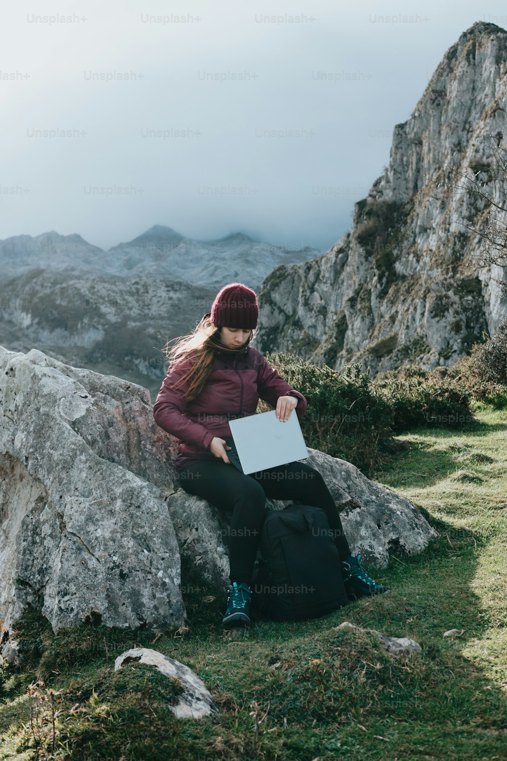 a woman sitting on a rock with a laptop