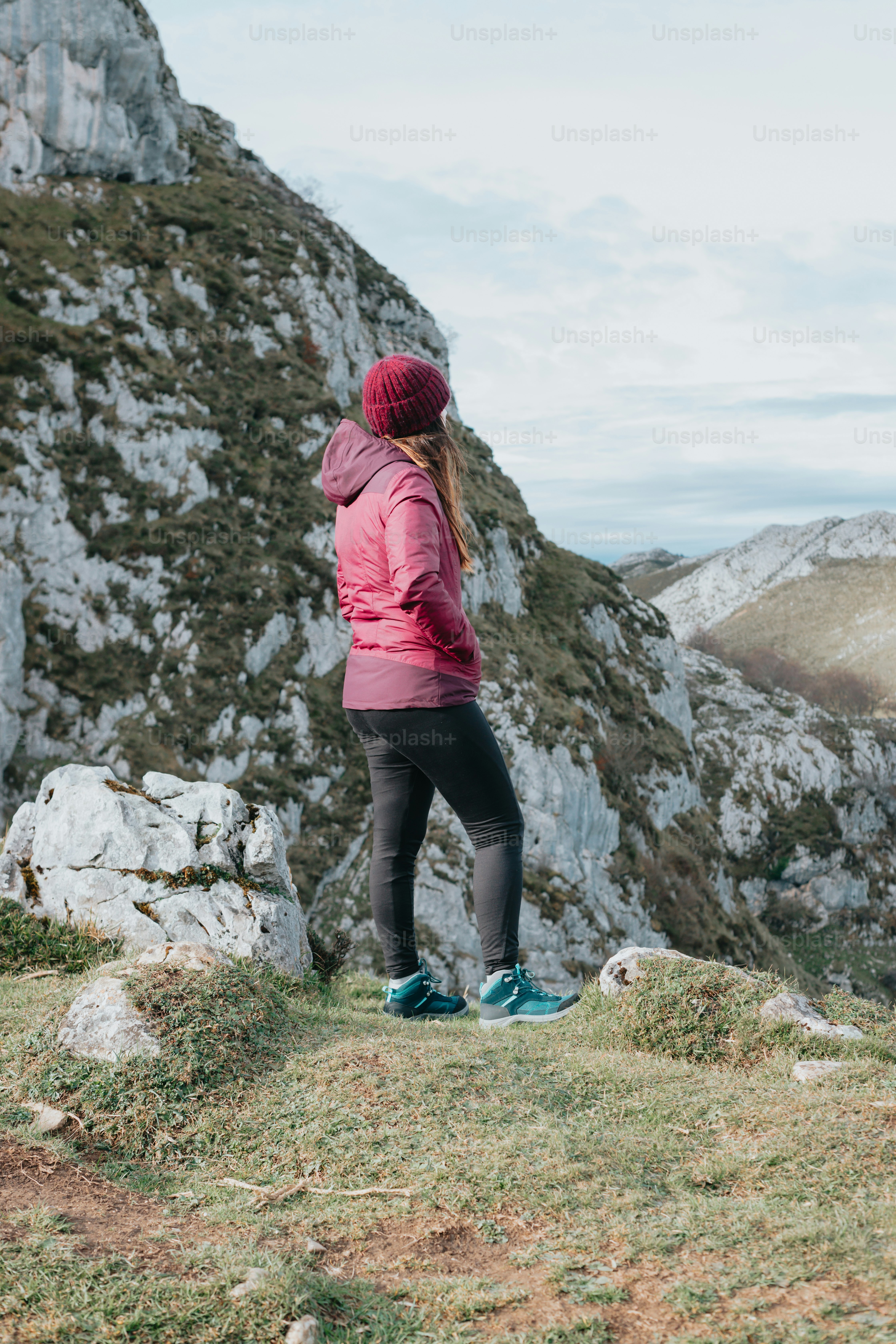 a woman standing on top of a grass covered hillside