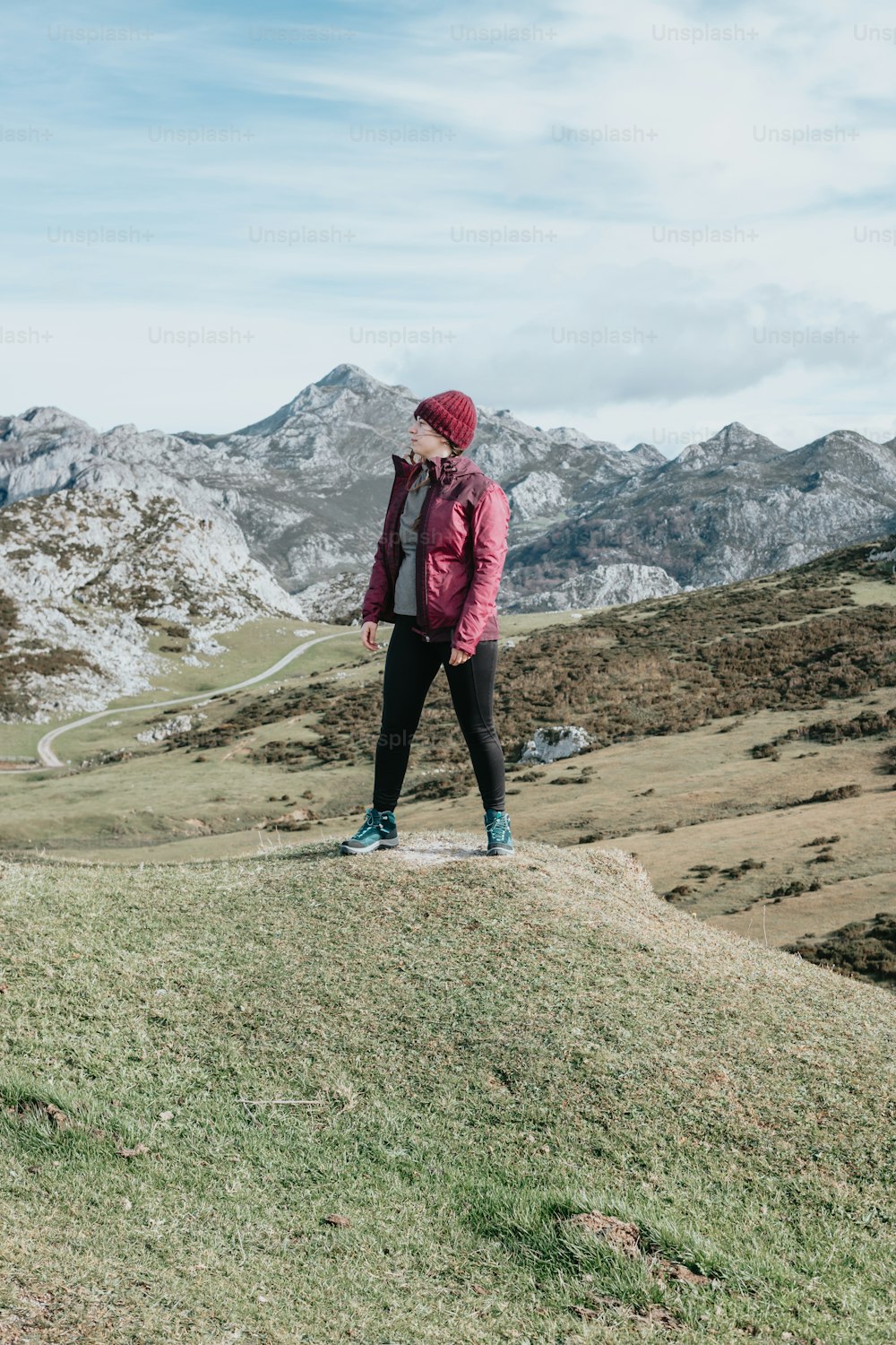 uma mulher em pé no topo de uma colina coberta de grama