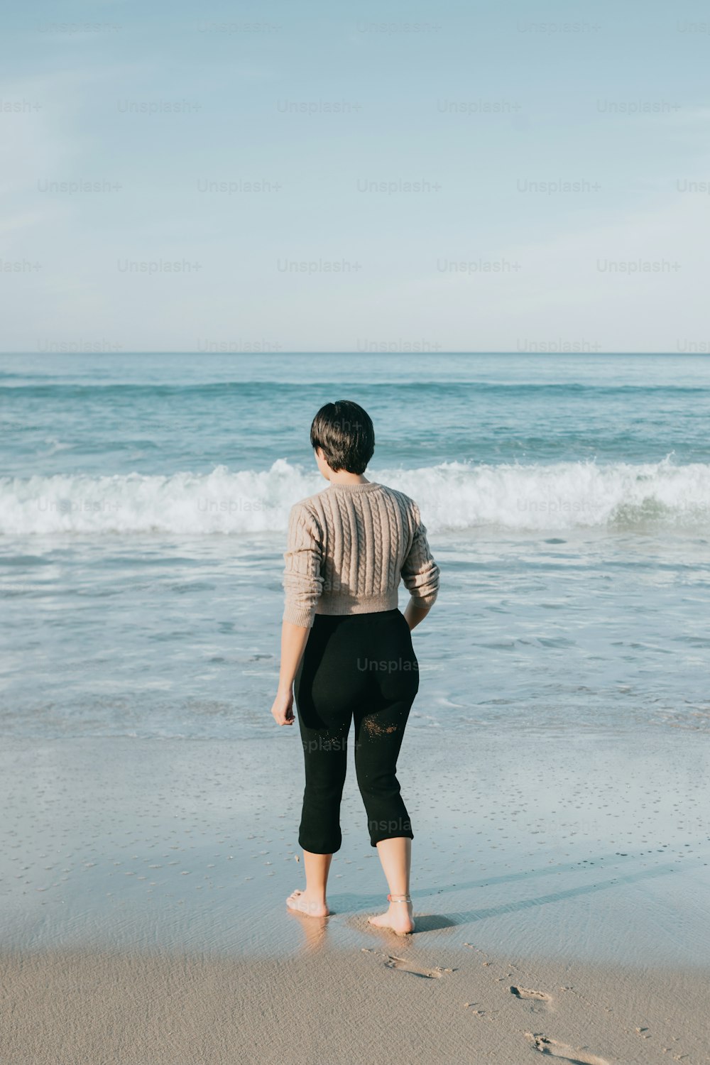 海の隣の砂浜の上に立つ女性