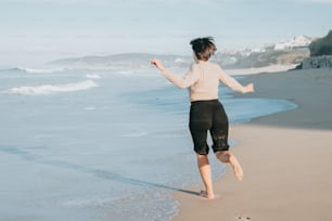 a woman running along the beach towards the ocean