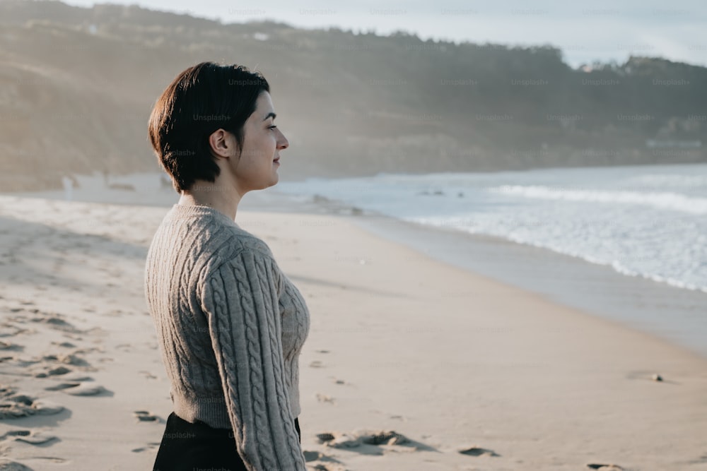 a woman standing on a beach next to the ocean