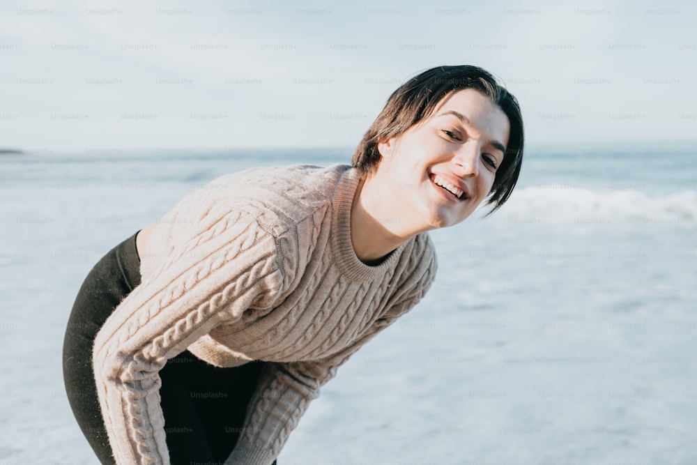 Une femme sourit alors qu’elle se tient sur la plage