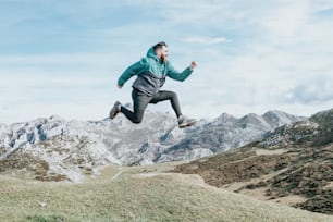 a man in a green jacket is jumping in the air