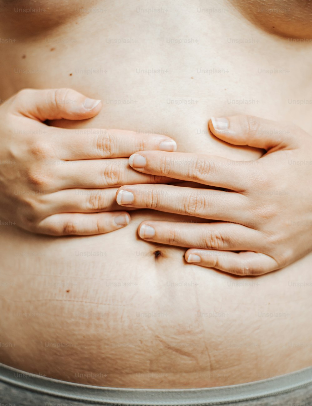a close up of a woman's stomach with her hands on her stomach