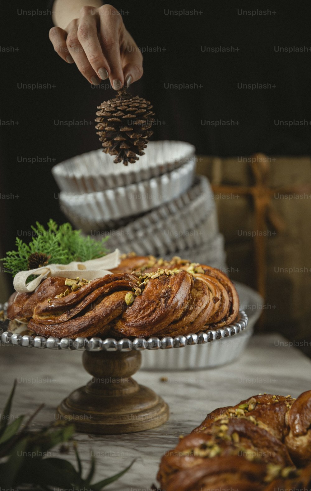 Una persona colocando un cono de pino encima de un pastel