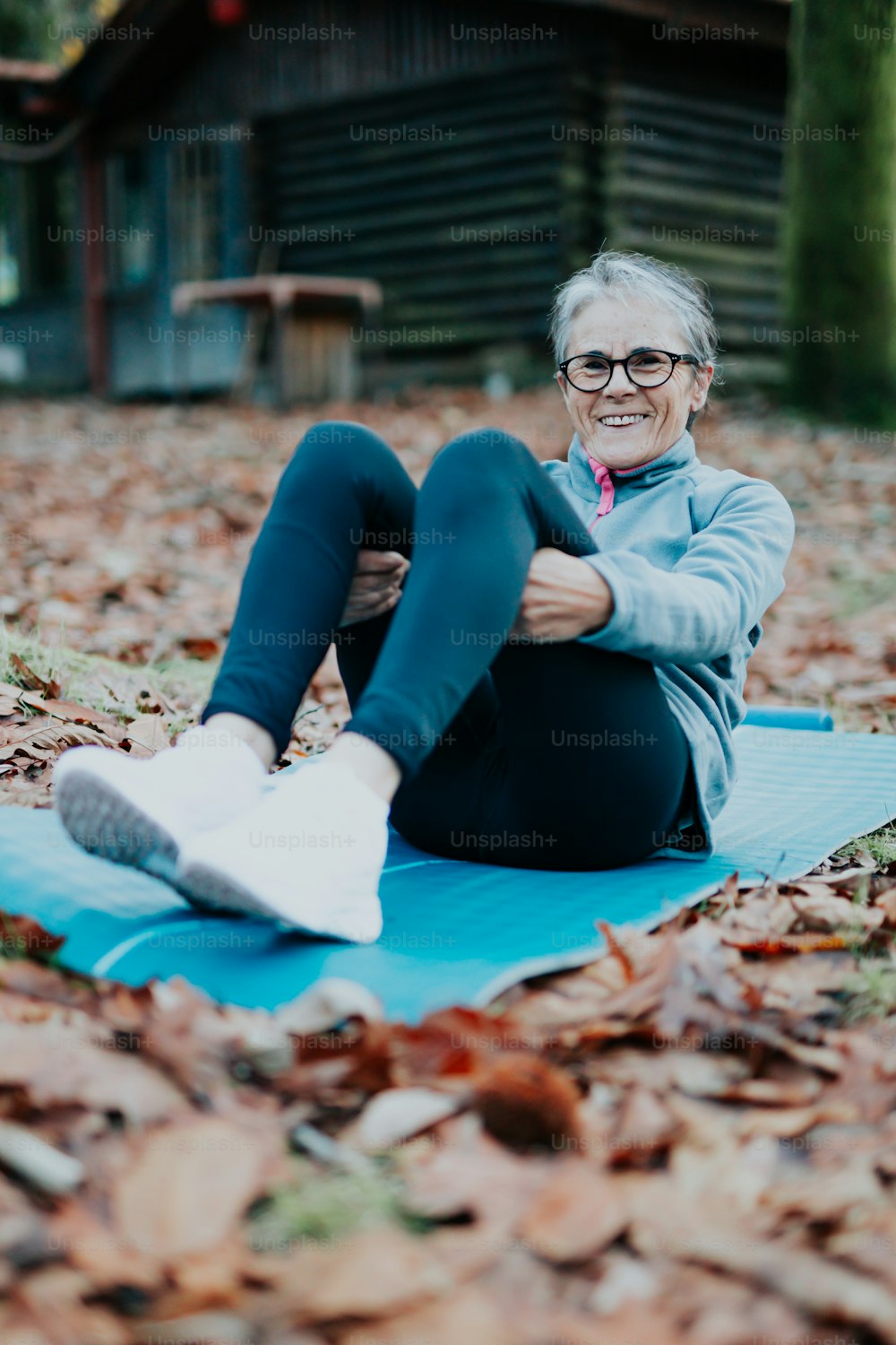 a woman sitting on a blue mat in the leaves