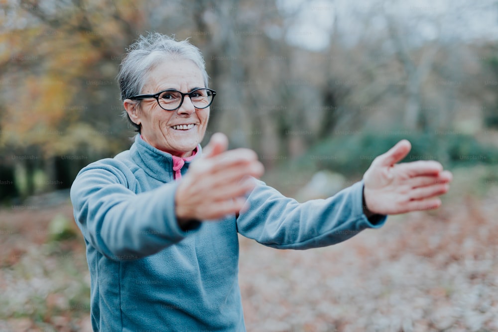 an older woman wearing glasses standing in a forest