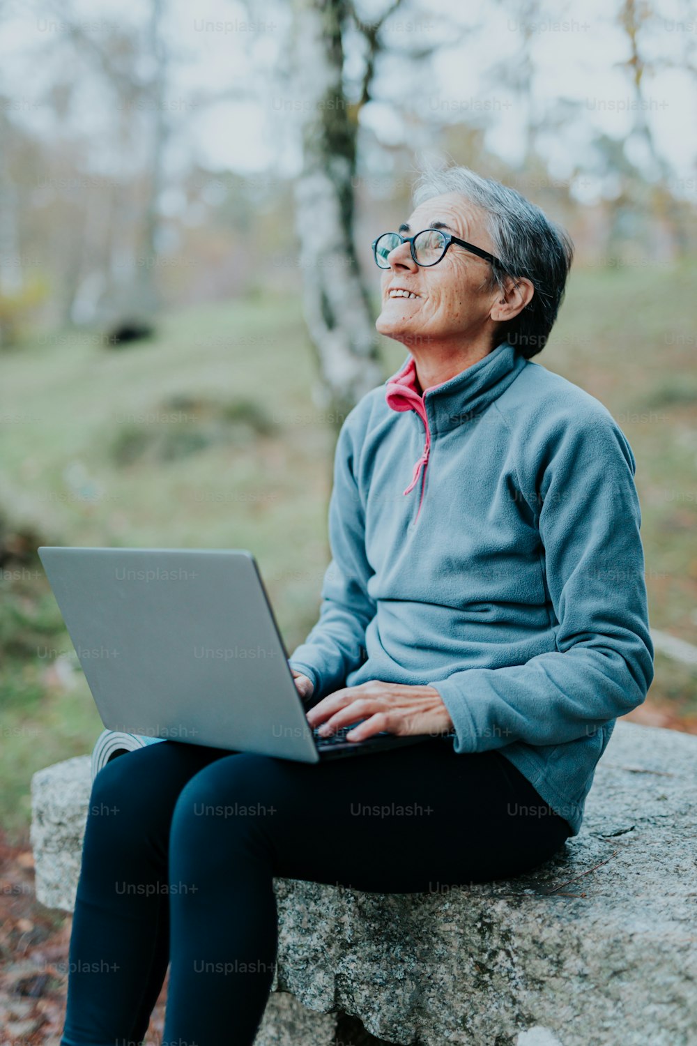 한 남자가 노트북 컴퓨터를 사용하여 바위 위에 앉아 있다