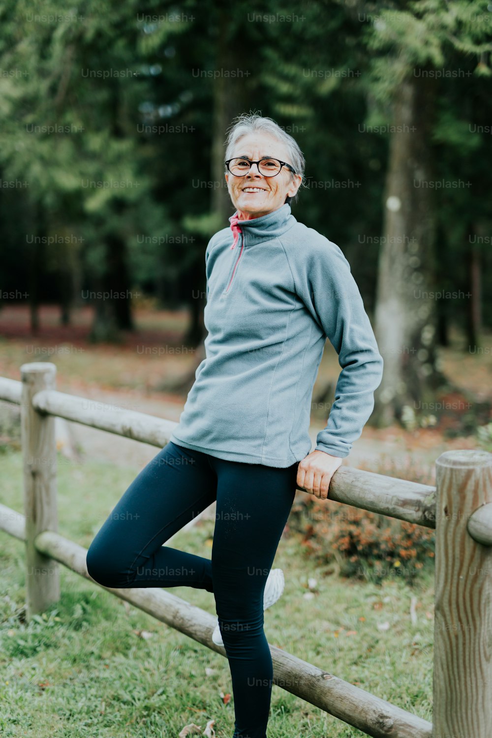 uma mulher em pé em uma cerca de madeira posando para uma foto