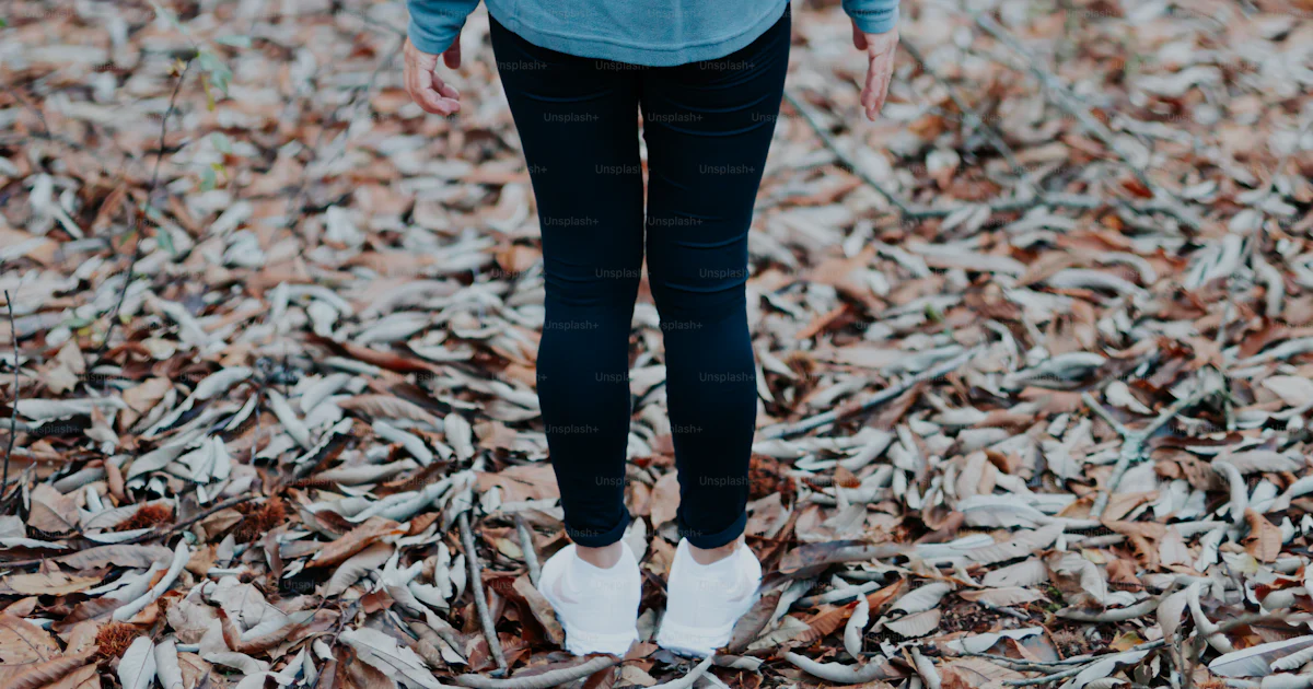 A woman walking through a leaf covered forest photo – Excising Image on ...