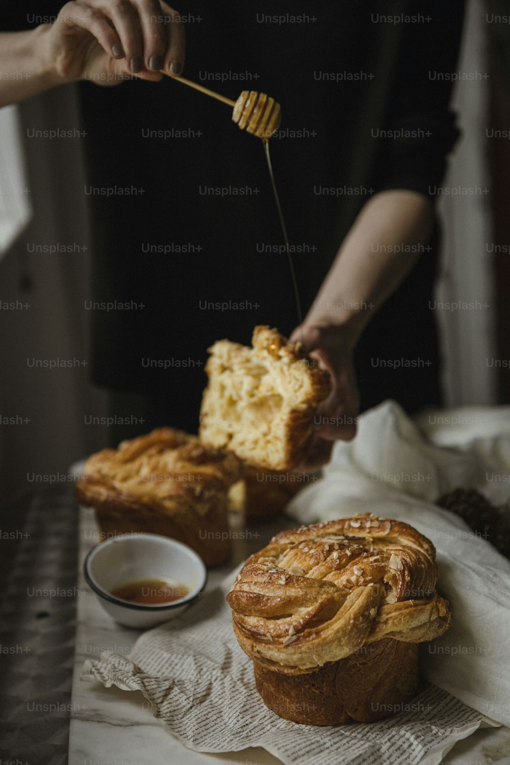 a person holding a honey comb over a pastry