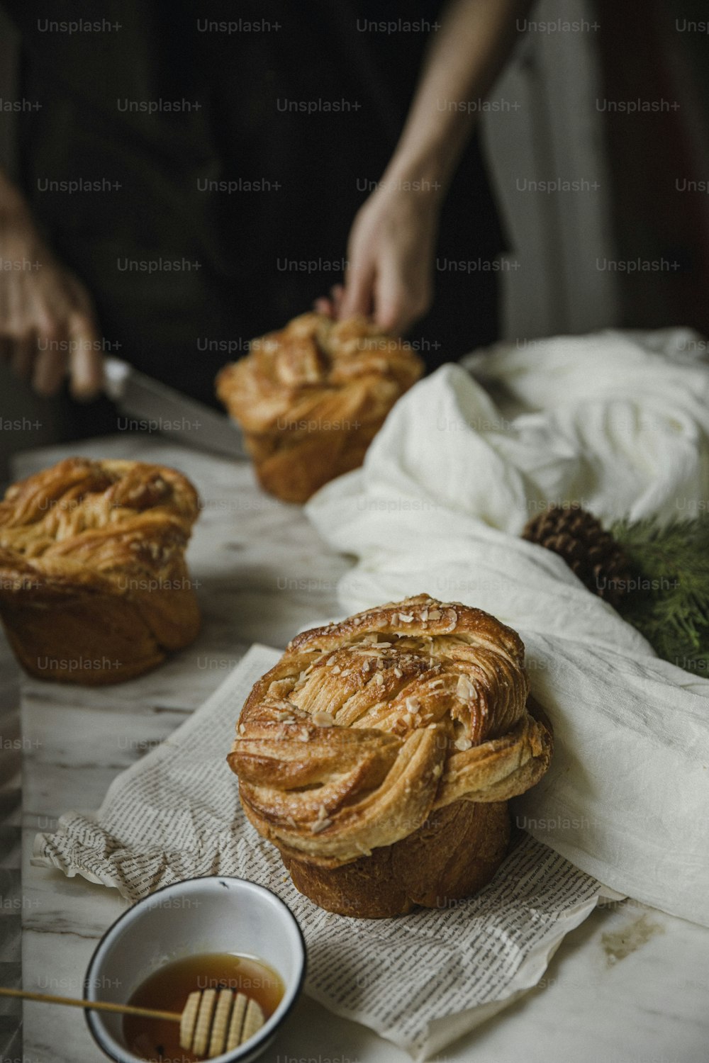 a table topped with pastries next to a bowl of syrup