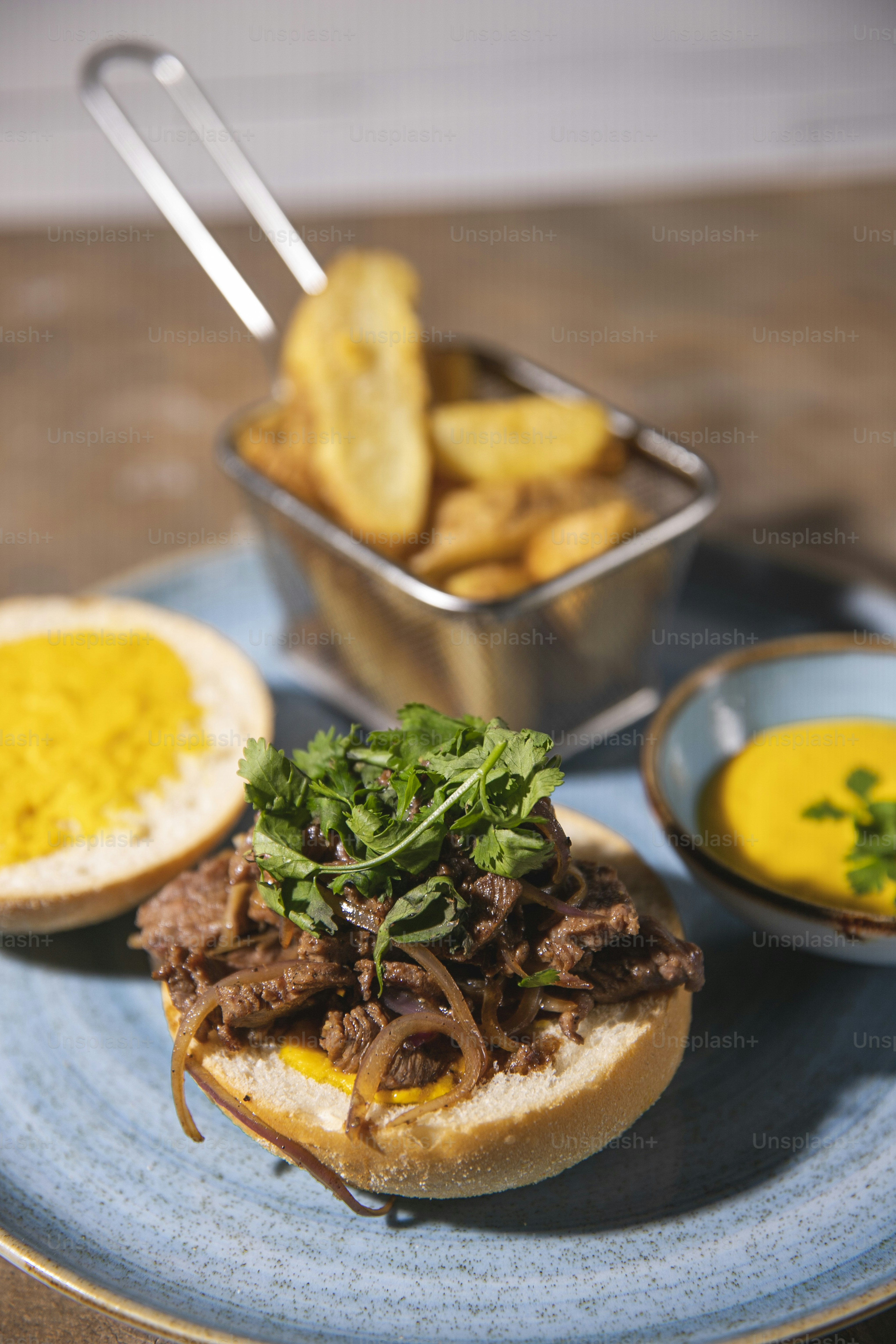 a blue plate topped with a sandwich and a bowl of mustard