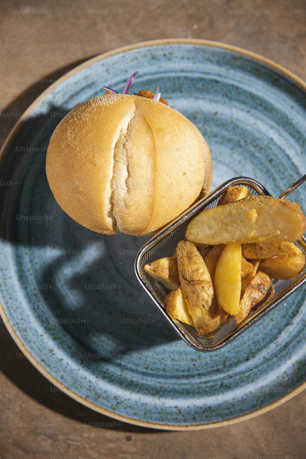 Un piatto blu condito con un panino e patatine fritte