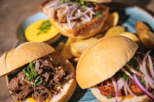 a blue plate topped with three pulled pork sandwiches