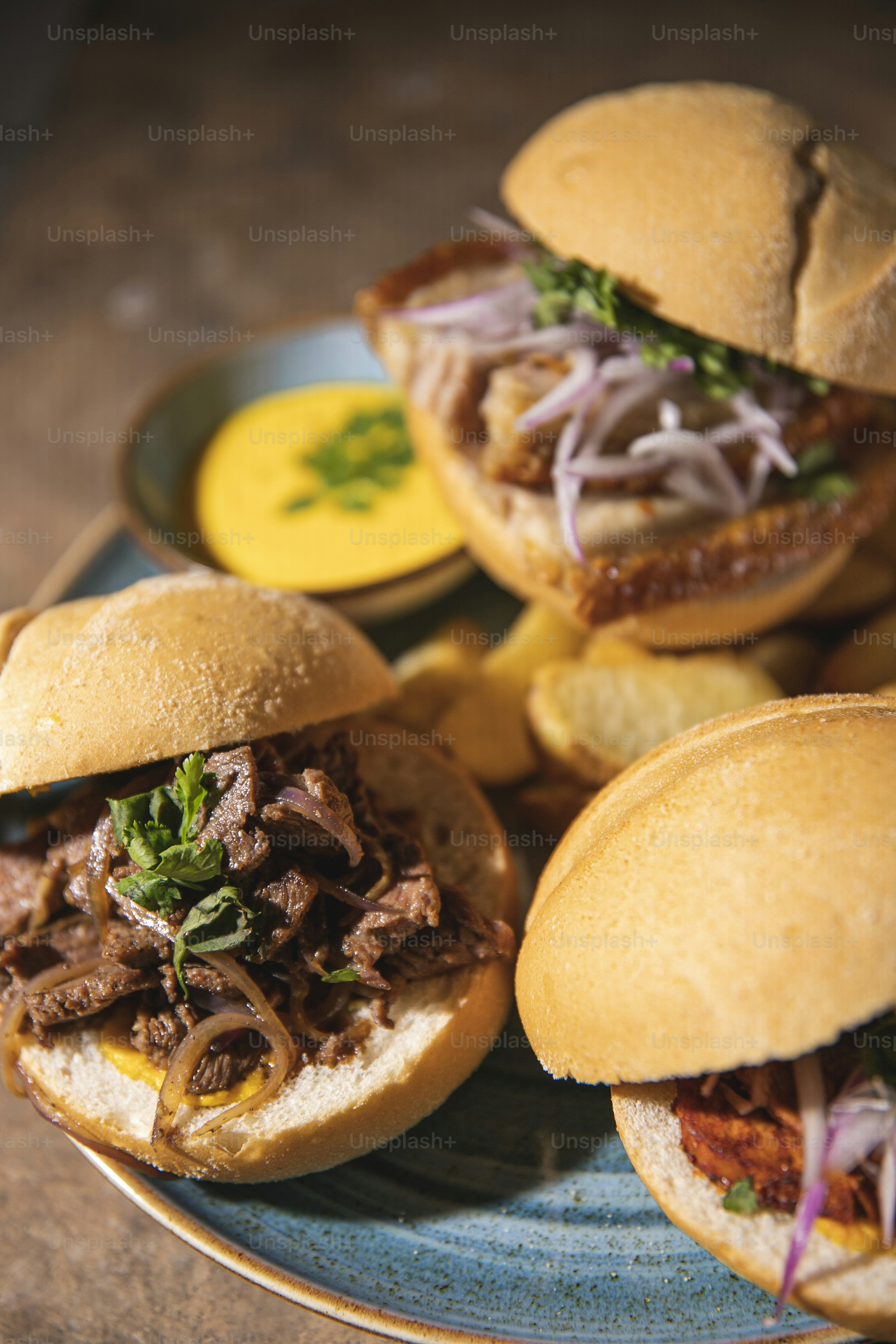 a blue plate topped with three pulled pork sandwiches