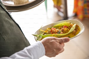 a person holding a plate of food on a table