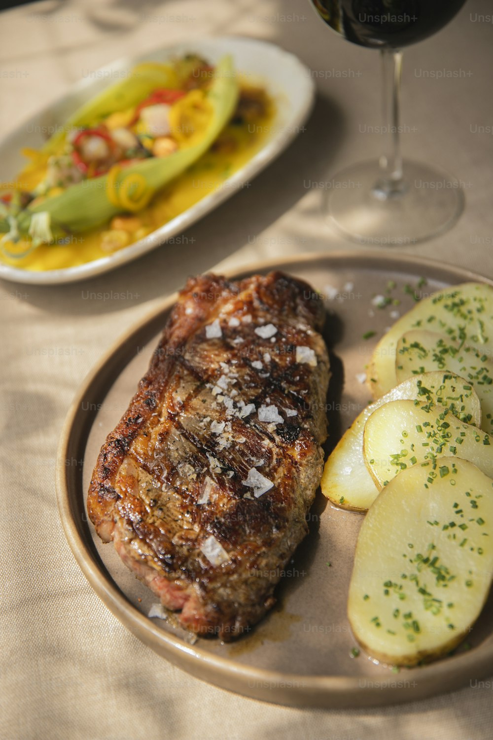 a plate of steak, potatoes and a glass of wine