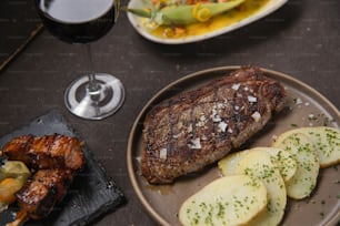 스테이크, 감자, 와인 한 잔이 테이블 위에 놓여 있다