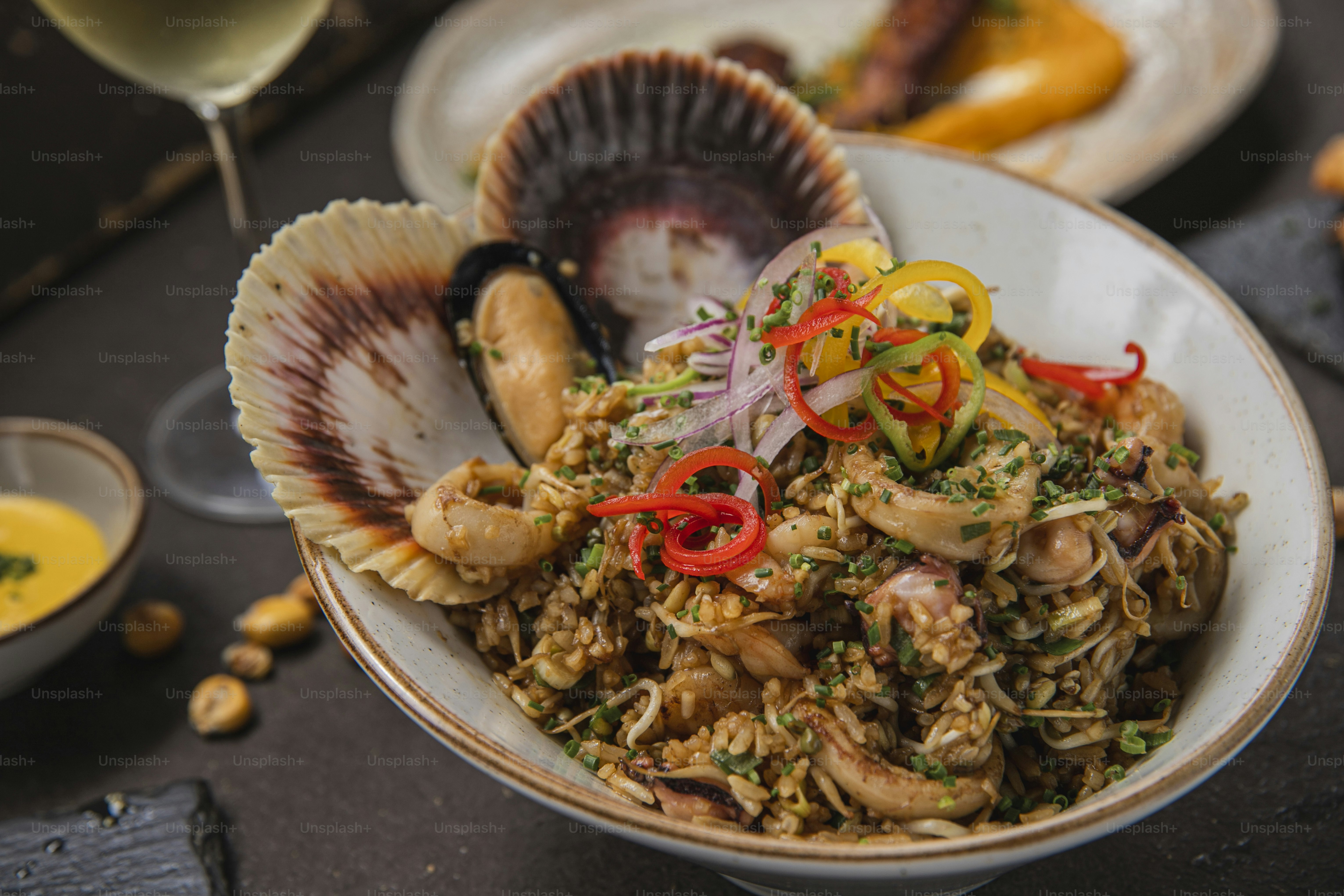 a bowl filled with food next to a glass of wine