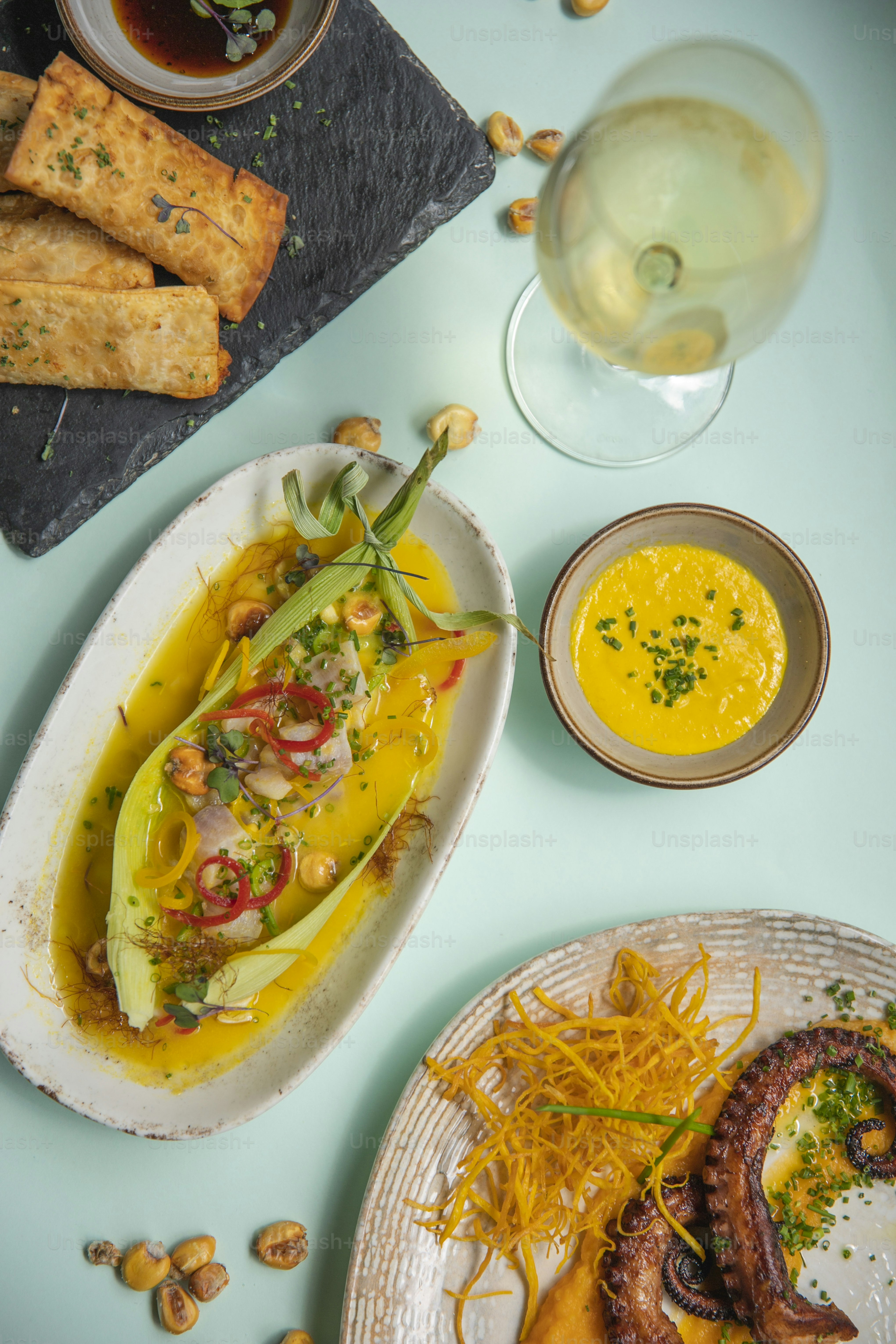a table topped with plates of food and a glass of wine