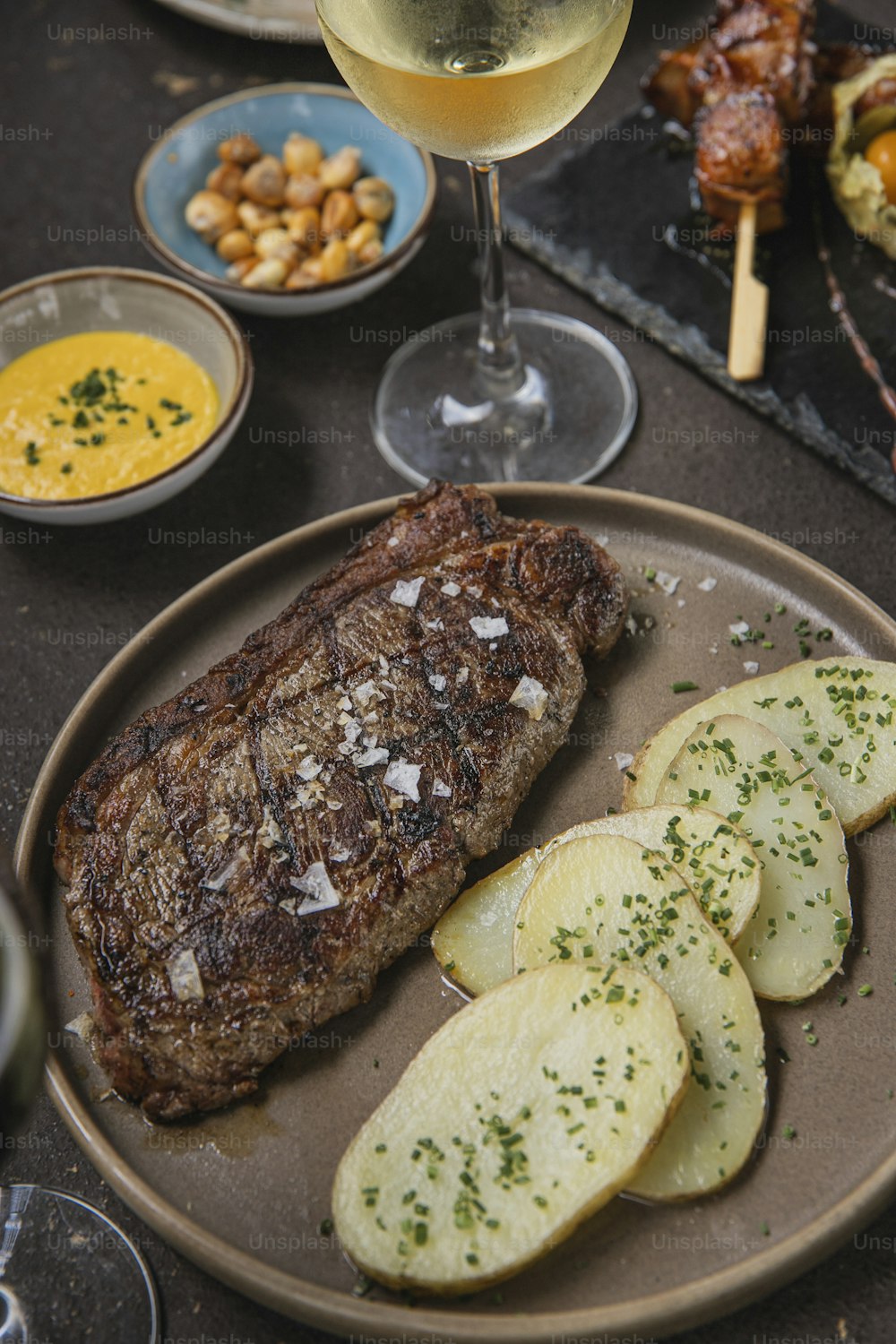 un plato de bistec, patatas y una copa de vino