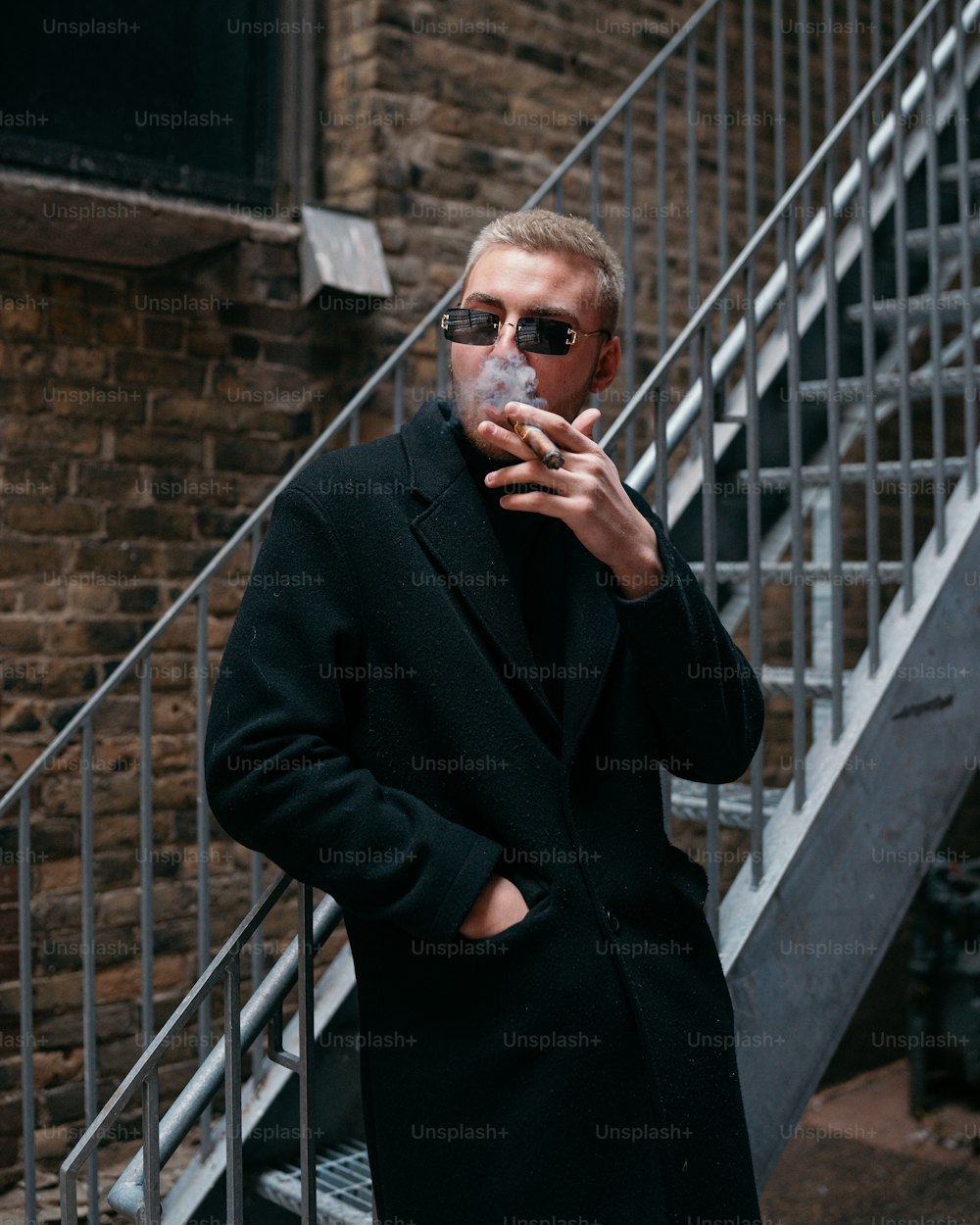 Un uomo in un cappotto nero che fuma una sigaretta