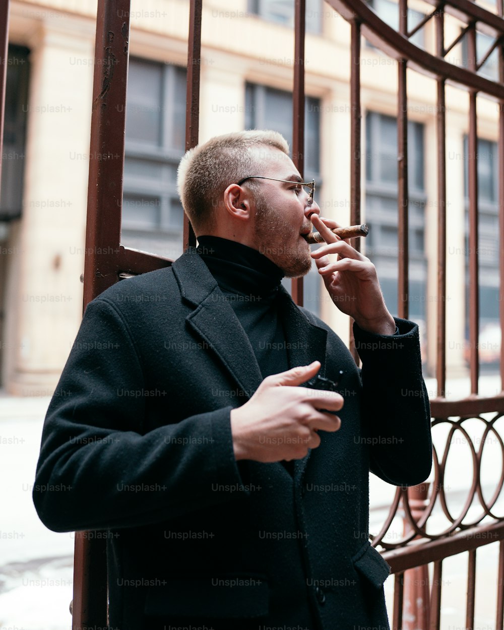 a man smoking a cigarette in front of a gate