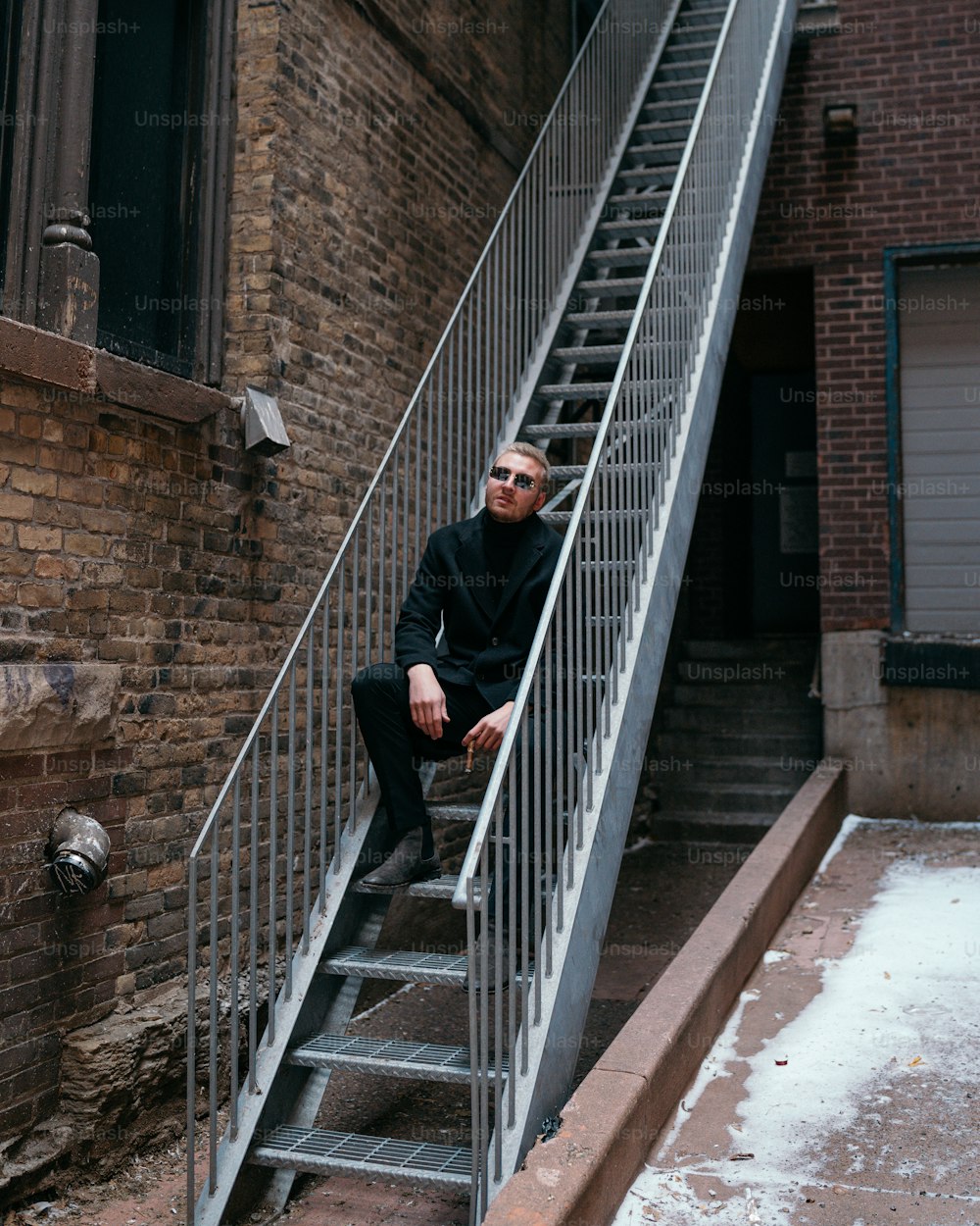 a man sitting on a stair case next to a brick building