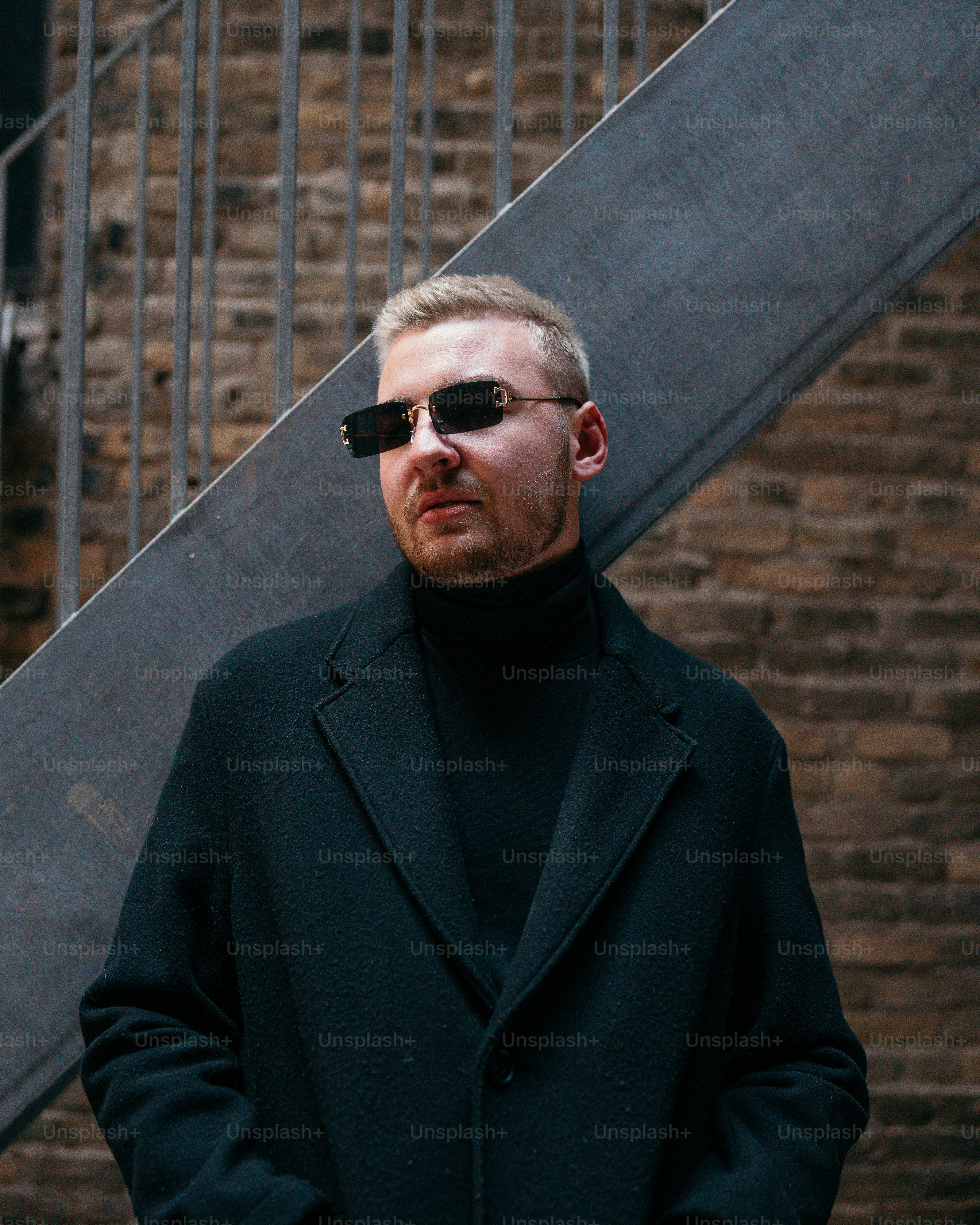 a man wearing sunglasses standing in front of a stair case