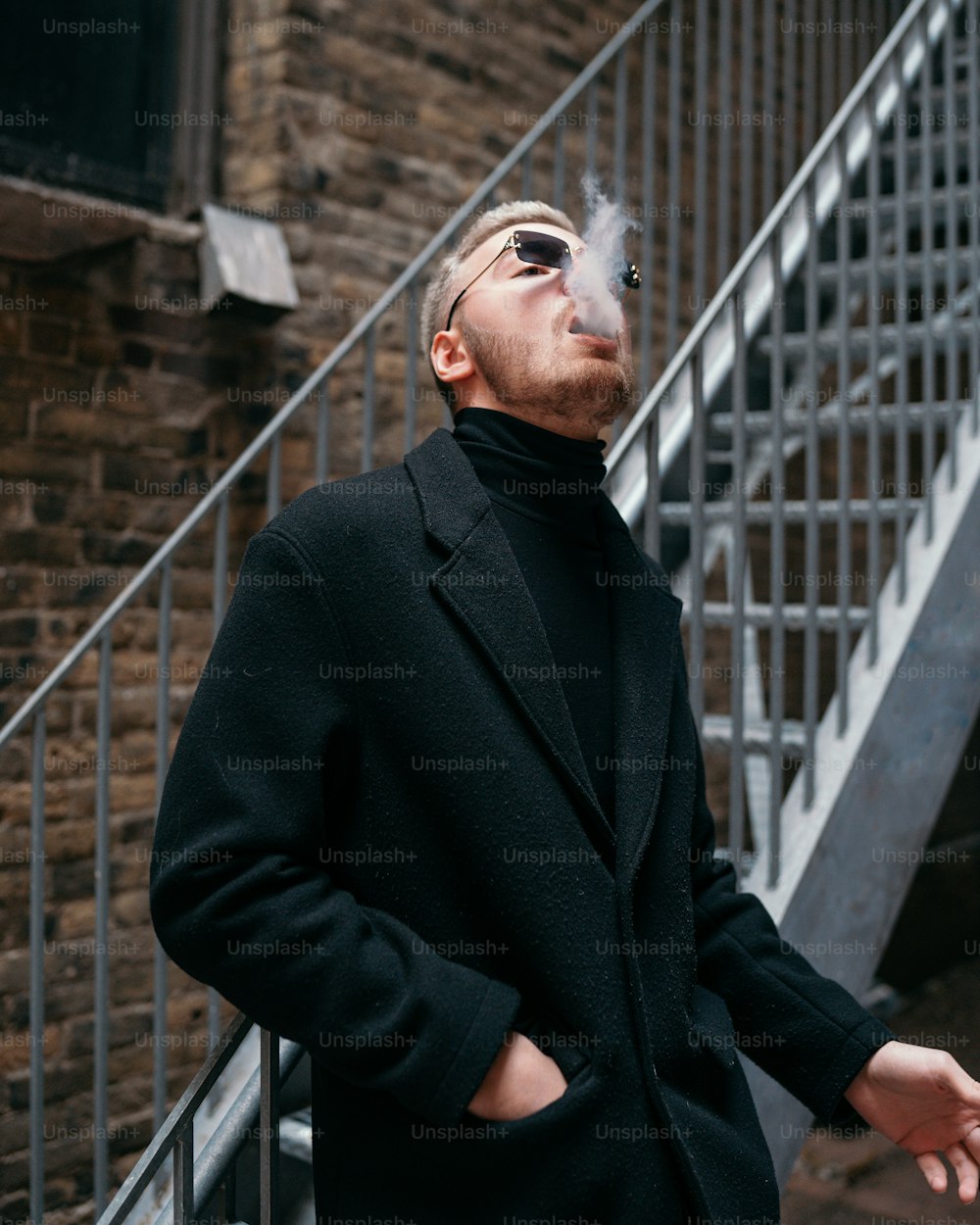 a man smoking a cigarette in front of a stair case
