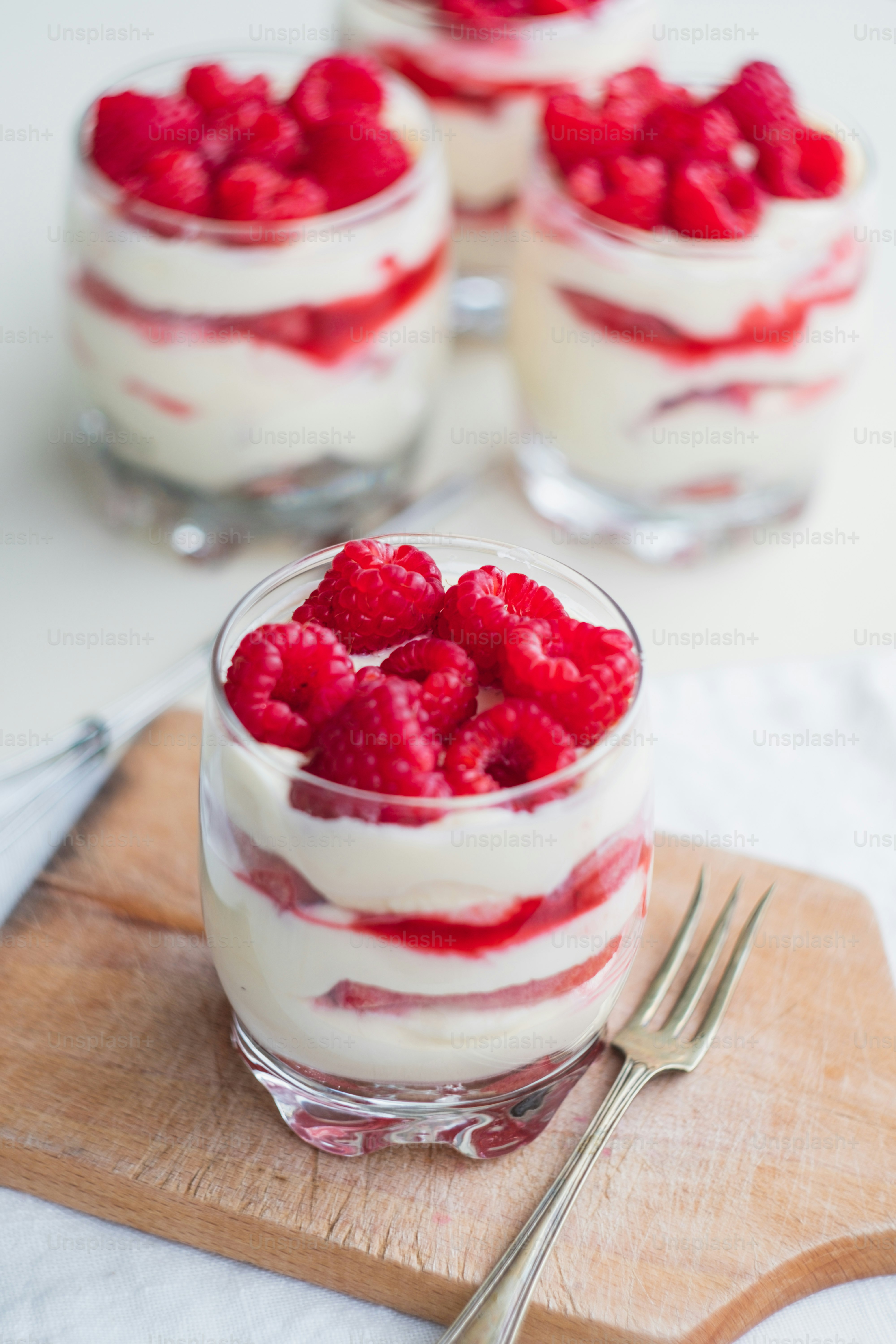 Kleine Desserts mit Himbeeren und Schlagsahne auf einem Schneidebrett ...