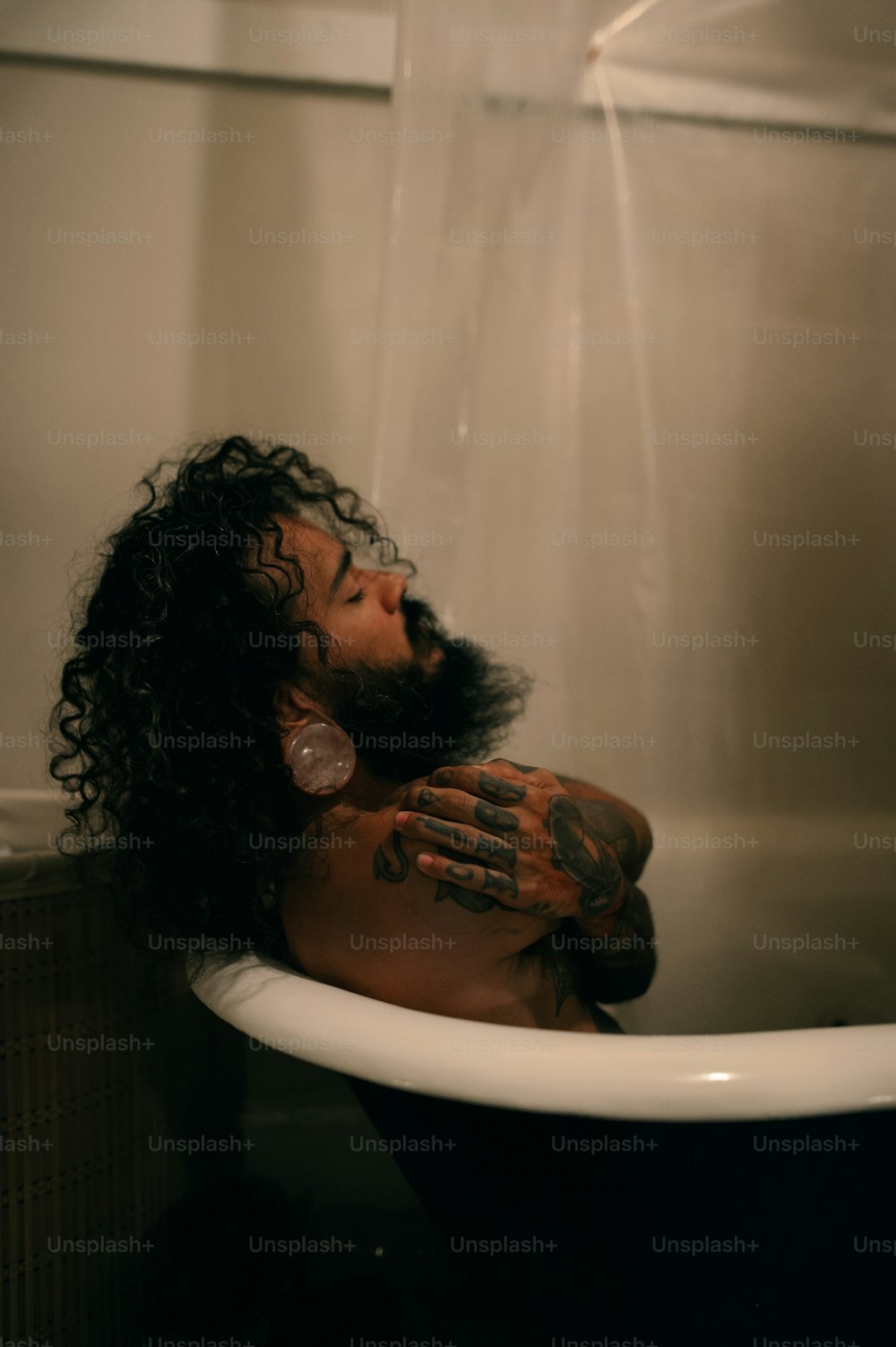 Un uomo in una vasca da bagno coperta di tatuaggi