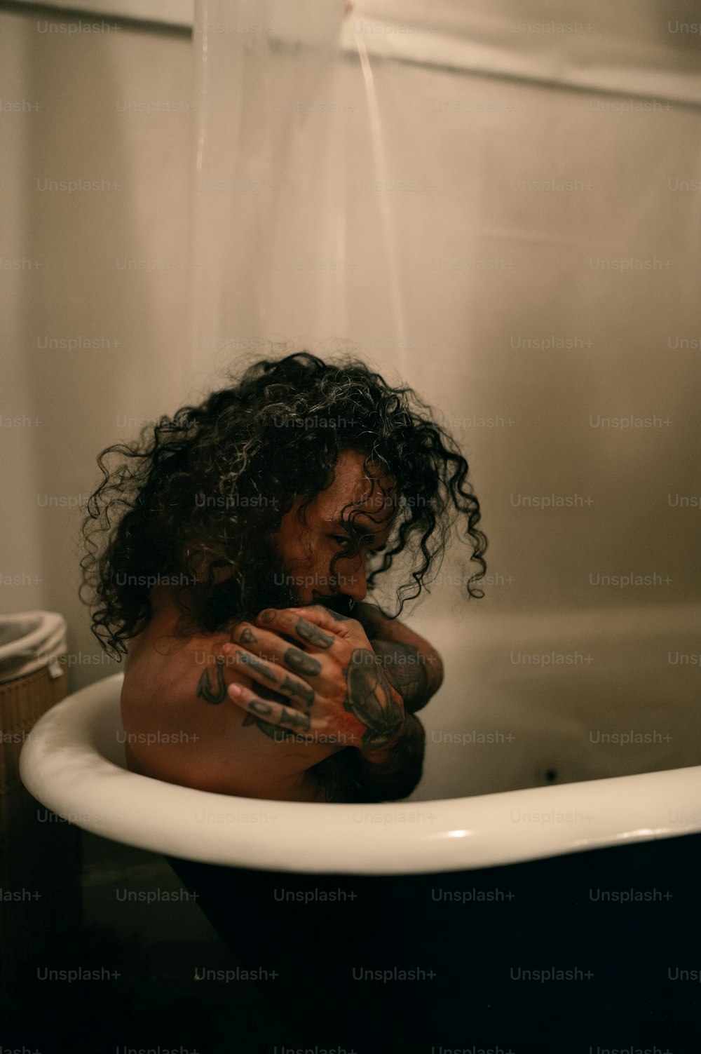 Un uomo coperto di tatuaggi seduto in una vasca da bagno