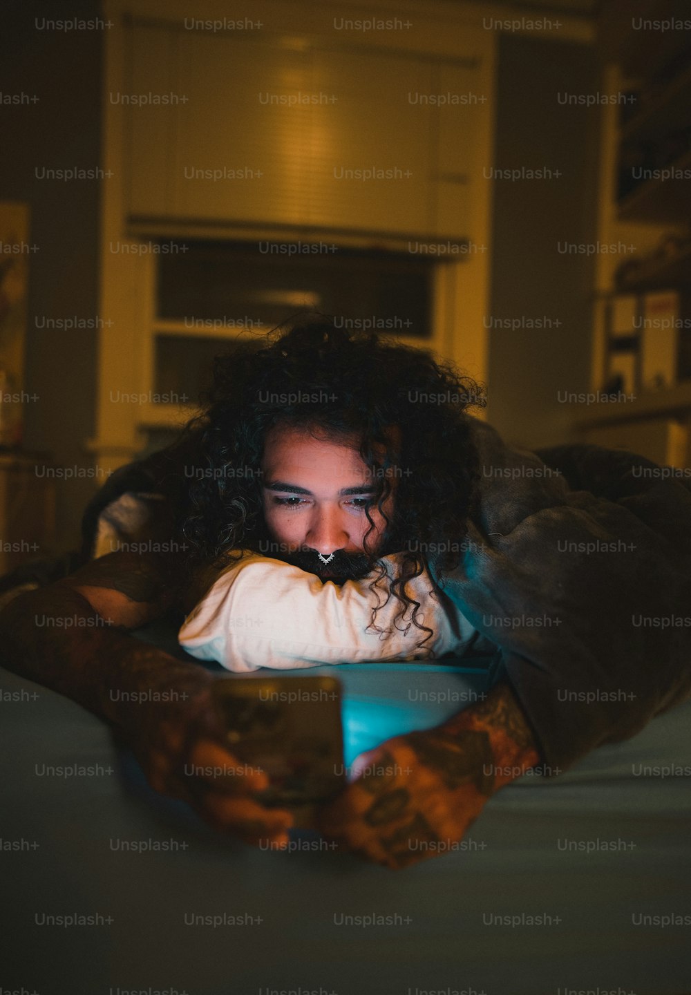 uma mulher deitada em uma cama olhando para um celular