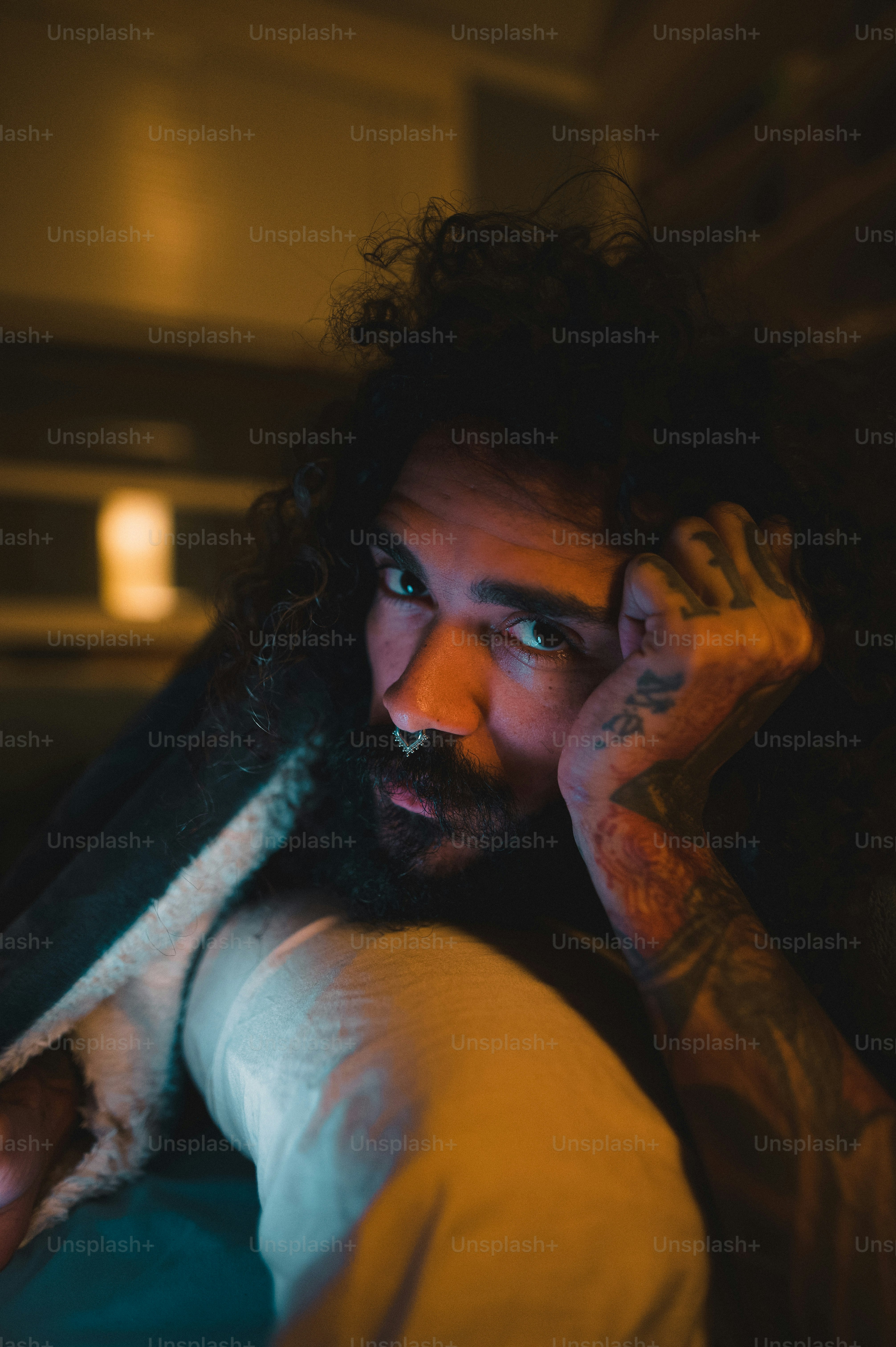 a man with long hair and a beard is holding his hand up to his face