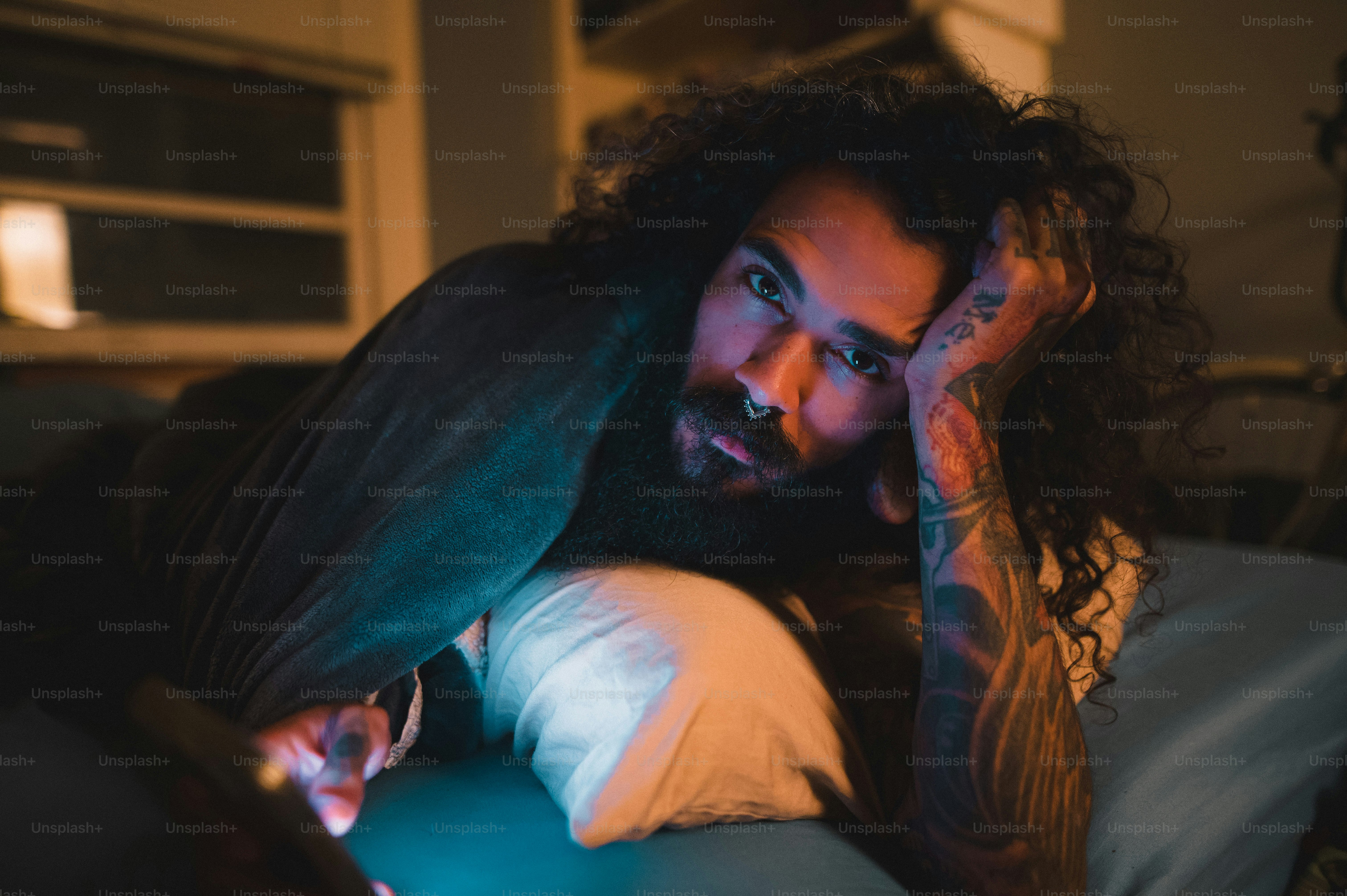 a man with long hair and a beard laying on a bed