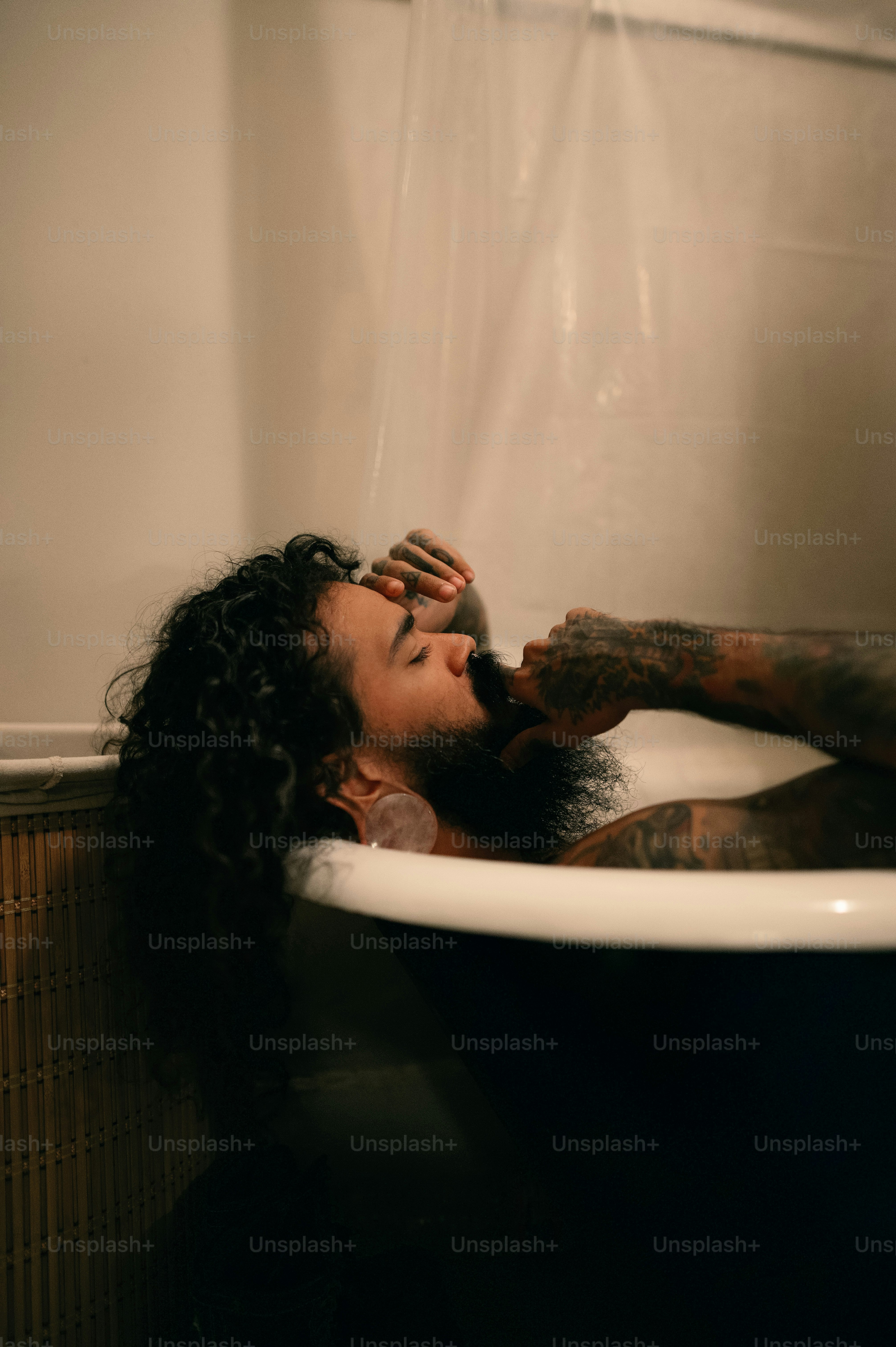 a man laying in a bathtub with long curly hair