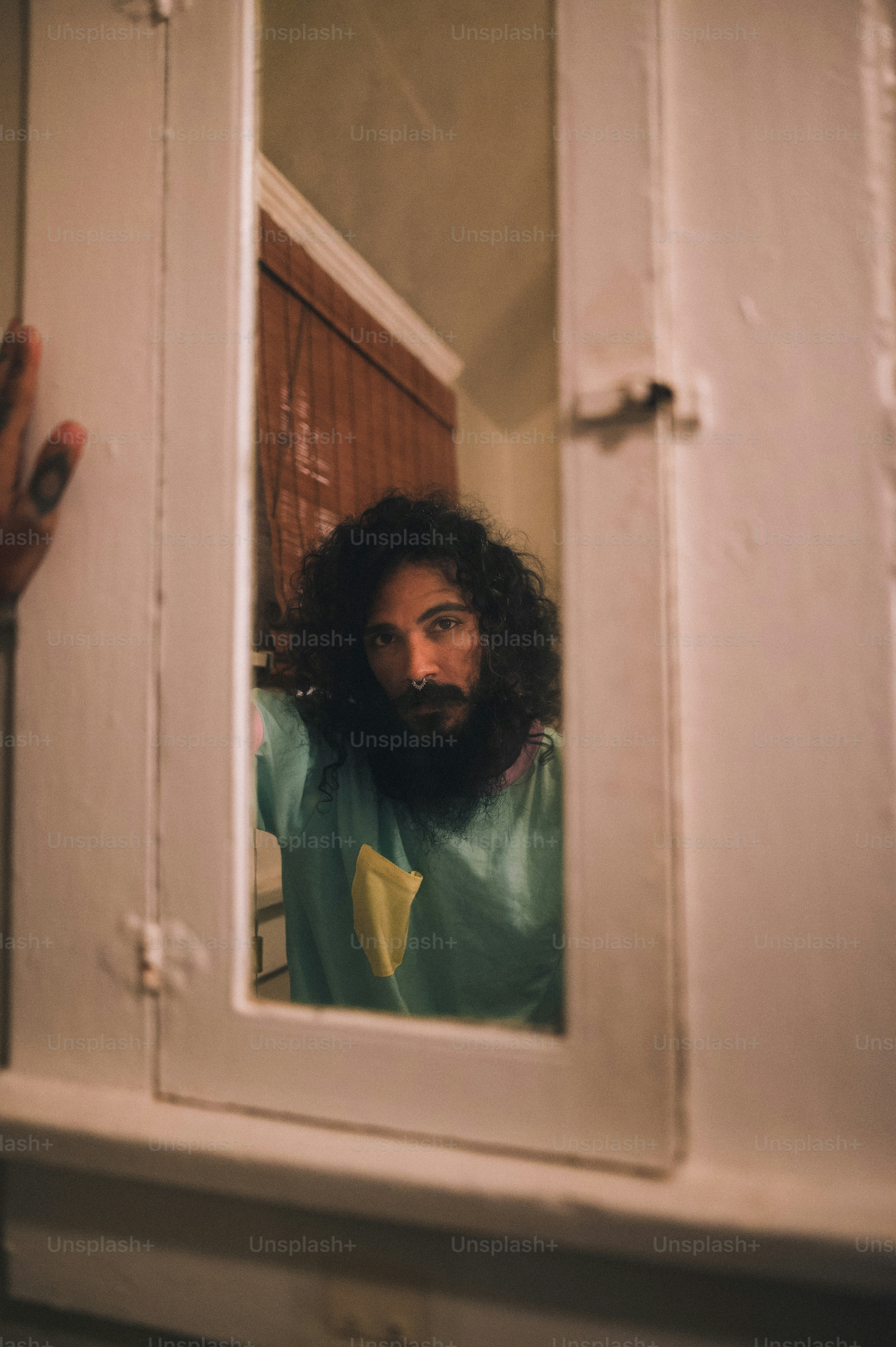 a man with long hair and a beard standing in front of a mirror