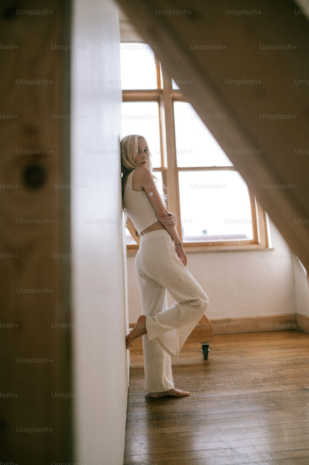 a woman in a white top and pants standing in a room