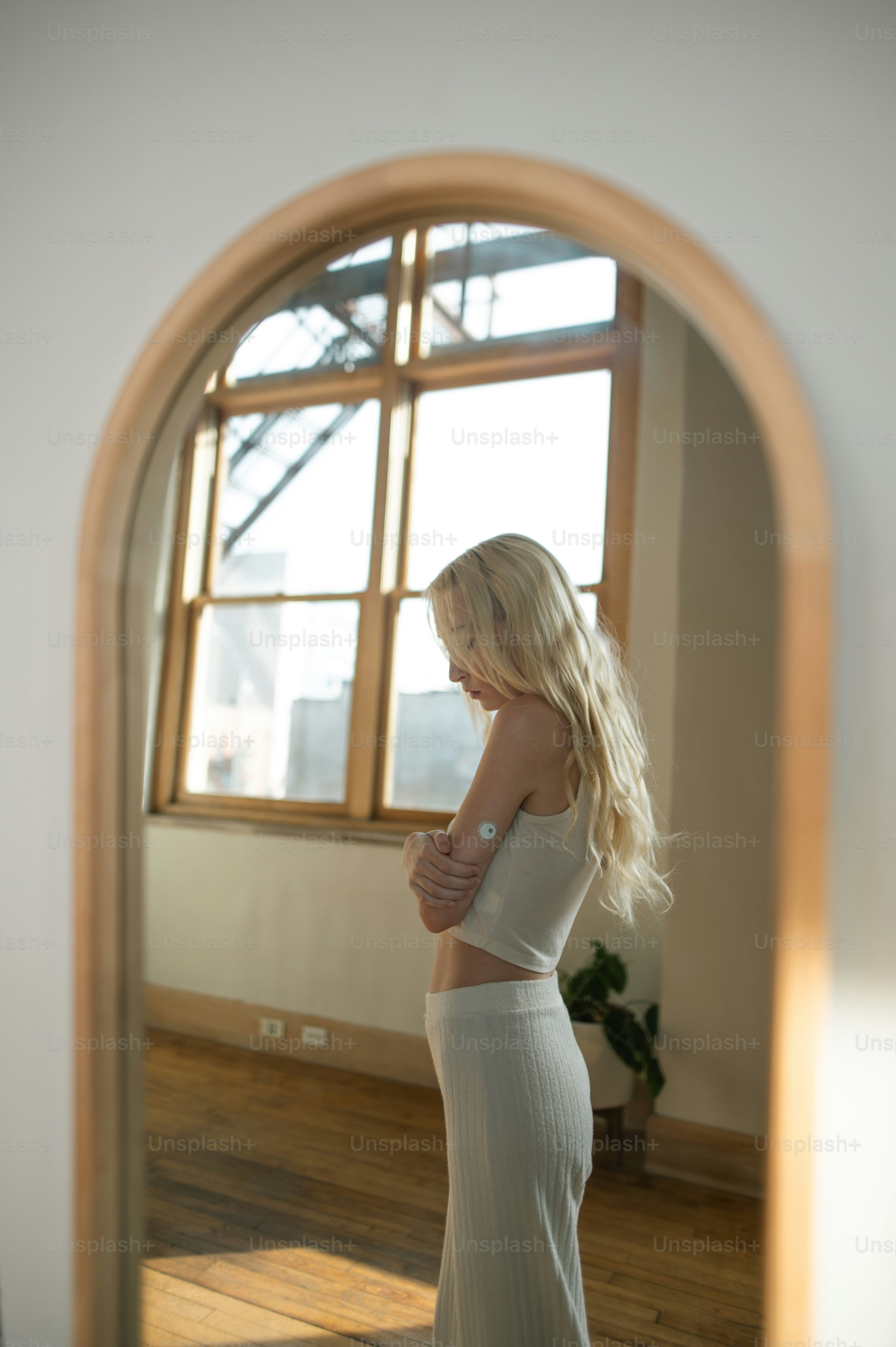 a woman in a white dress standing in front of a window