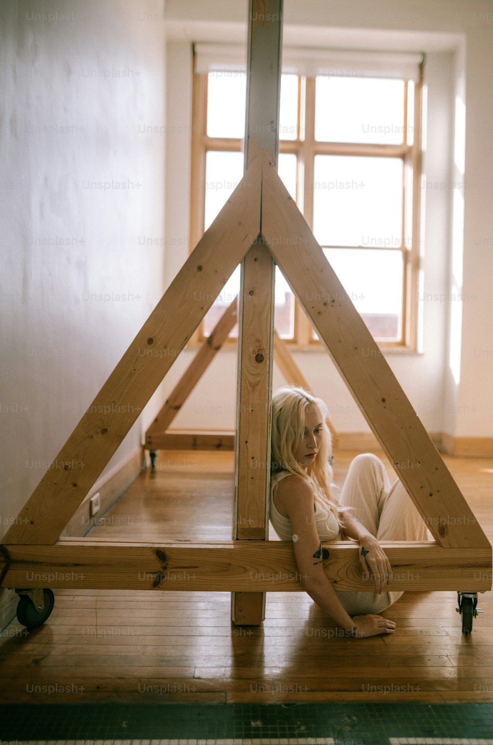a woman sitting on the floor in front of a wooden structure