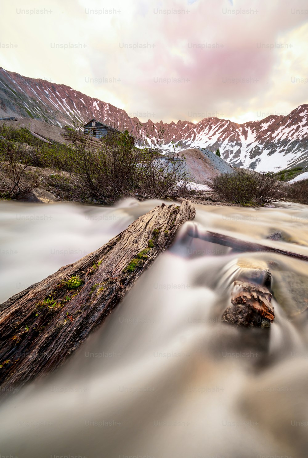a long exposure photo of a river with mountains in the background