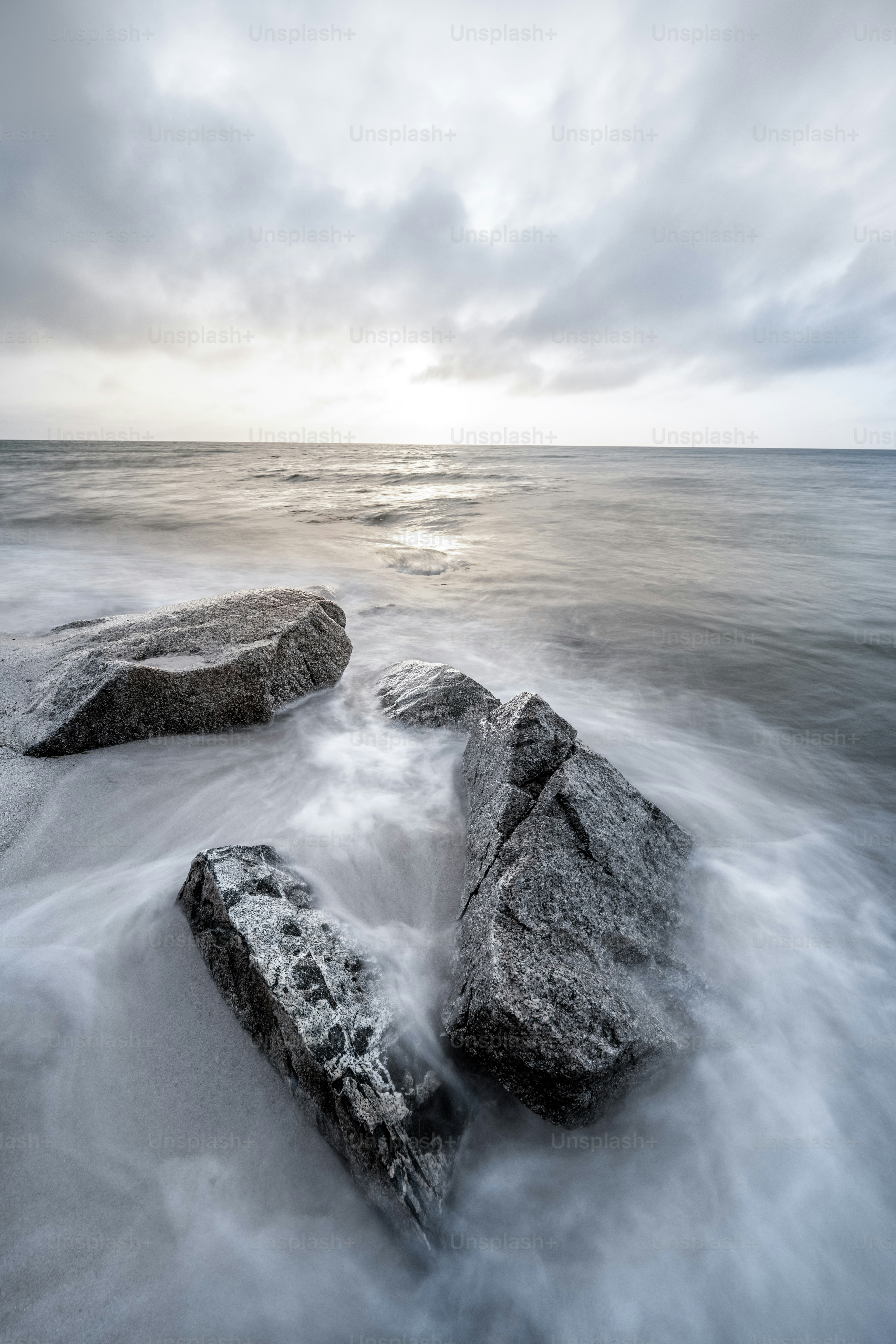 a couple of rocks sitting on top of a sandy beach
