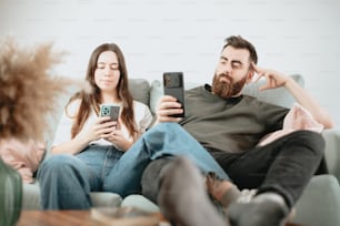 a group of people sitting on a couch looking at their phones