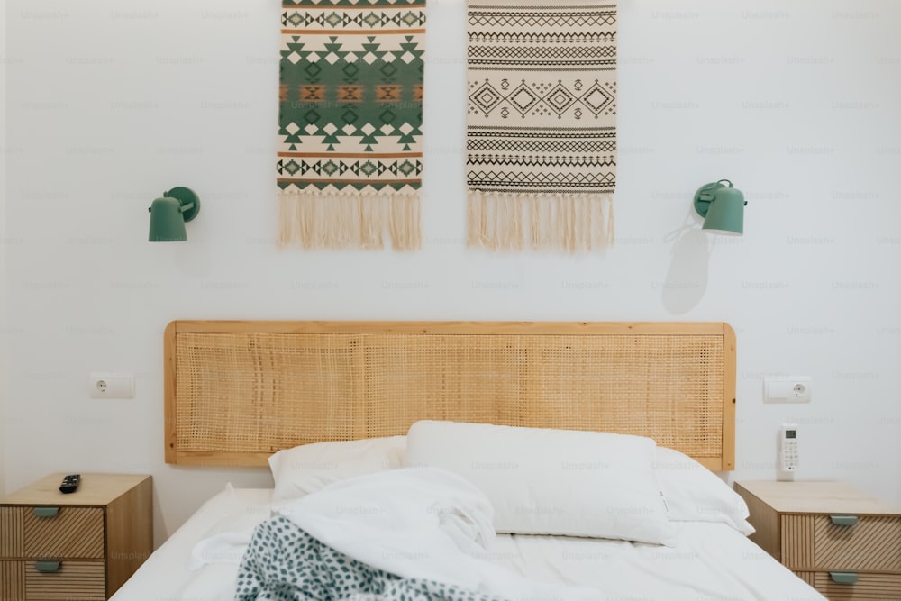 a bed with a white comforter and two wall hangings