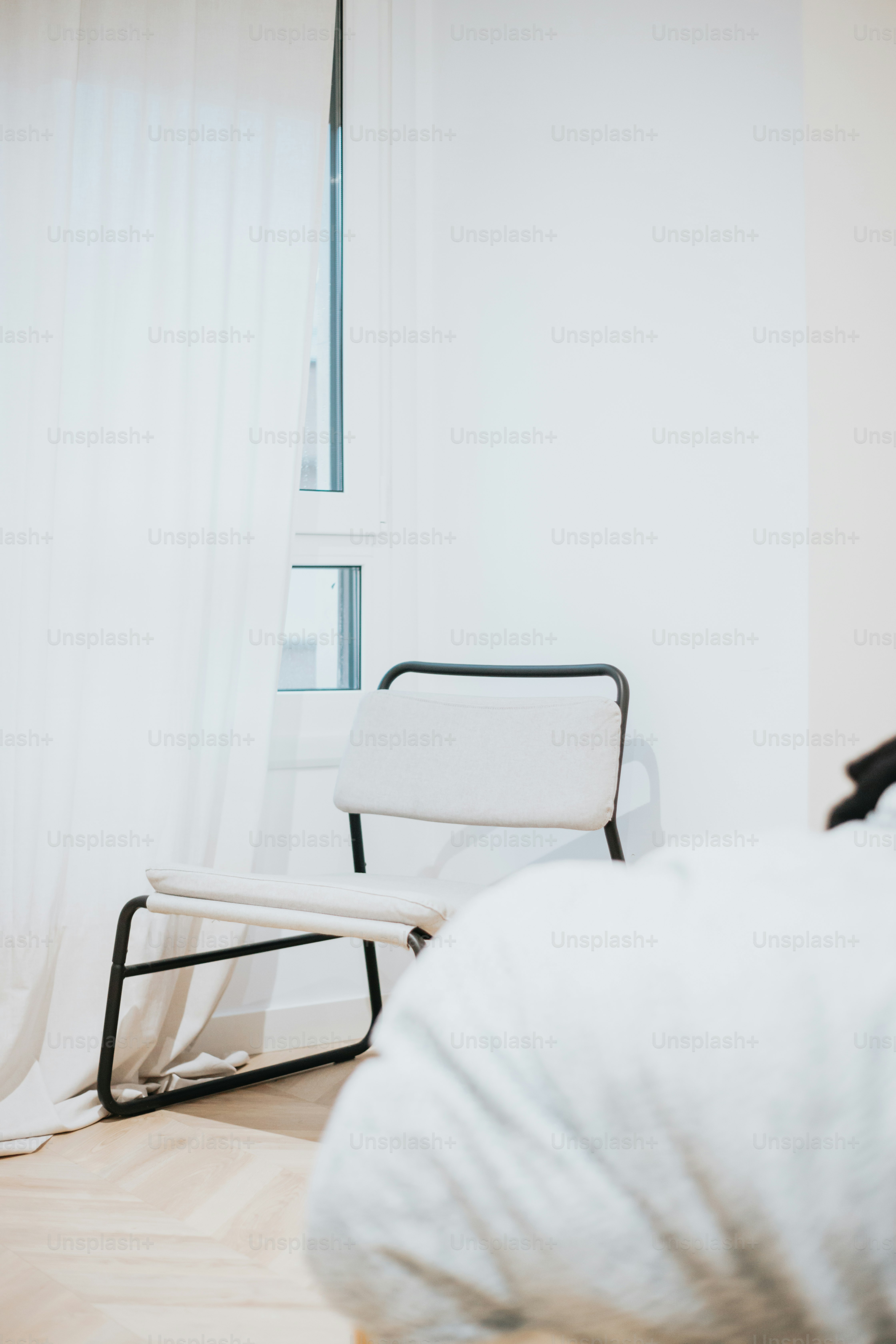 ein weißer Stuhl, der in einem Schlafzimmer neben einem Fenster sitzt