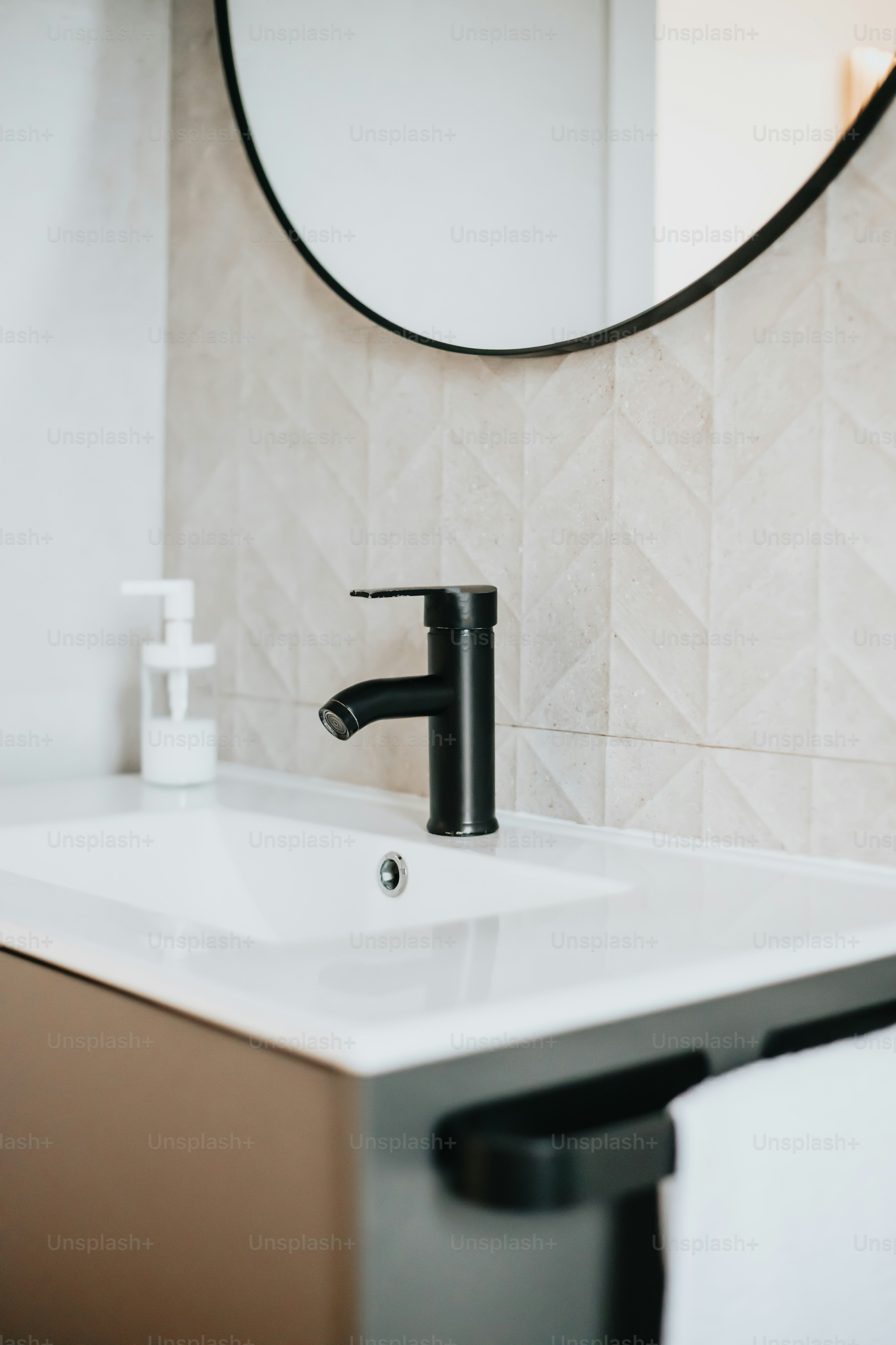 uma pia de banheiro com torneira preta e um espelho redondo