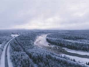 an aerial view of a road in the middle of a snowy forest